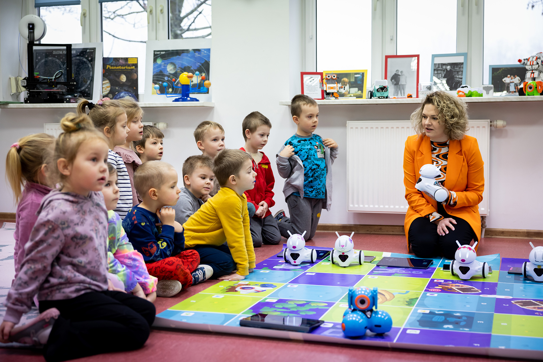 Pracownia Orange w Bulkowie. Przy macie dla robotów siedzi Natalia Maćkiewicz oraz grupa dzieci.
