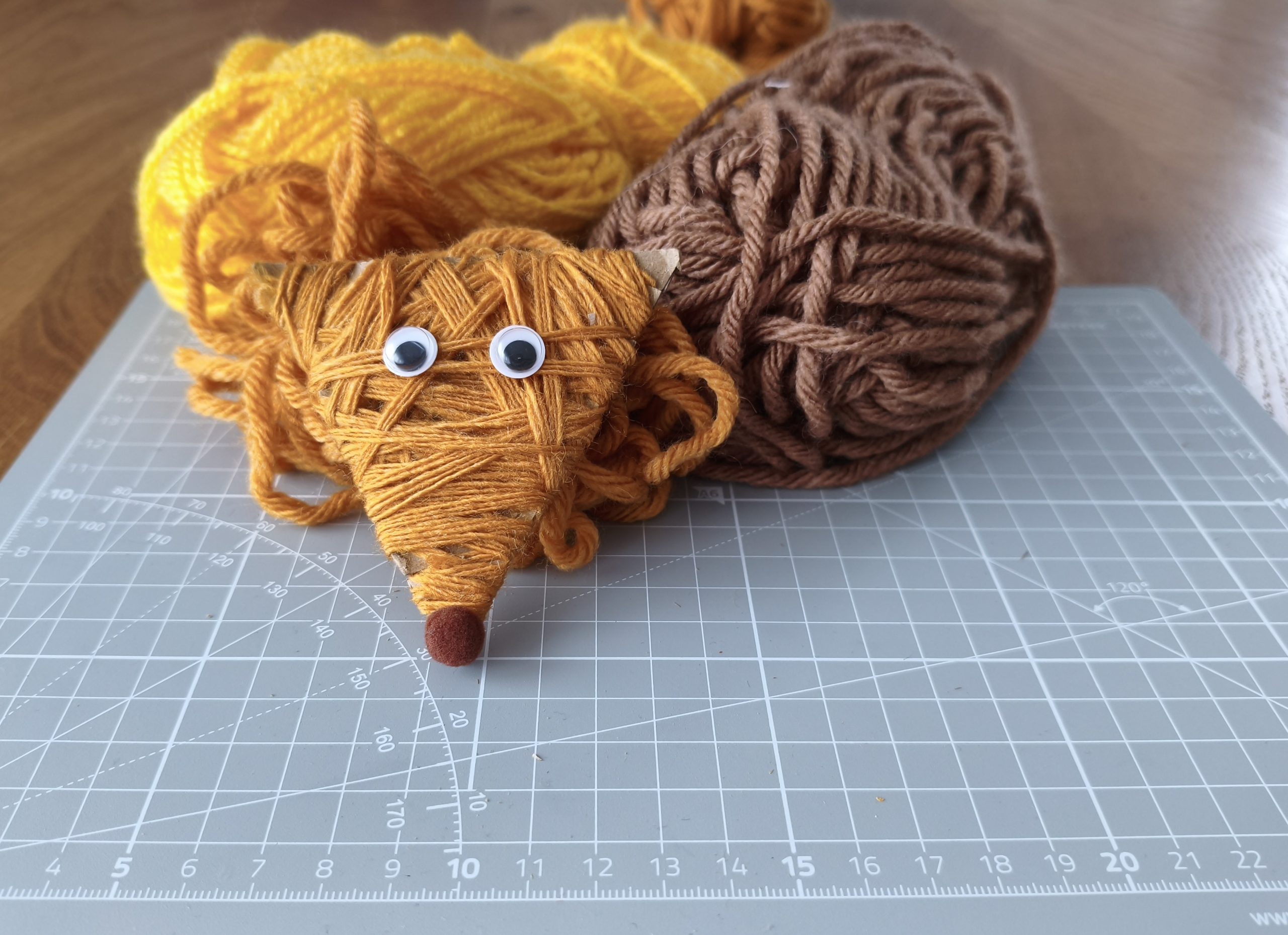 Gotowy lisek leżący na włóczkach.