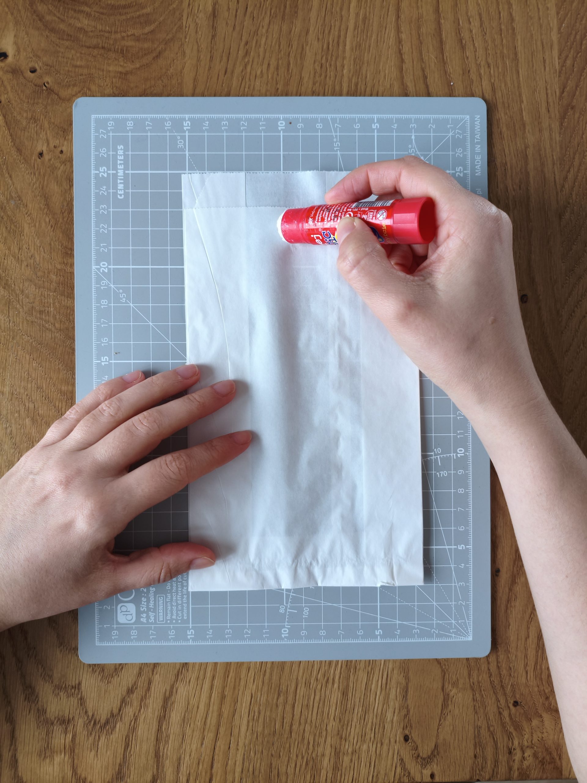 Zdjęcie przedstawiające dłonie klejące papierową torebkę.