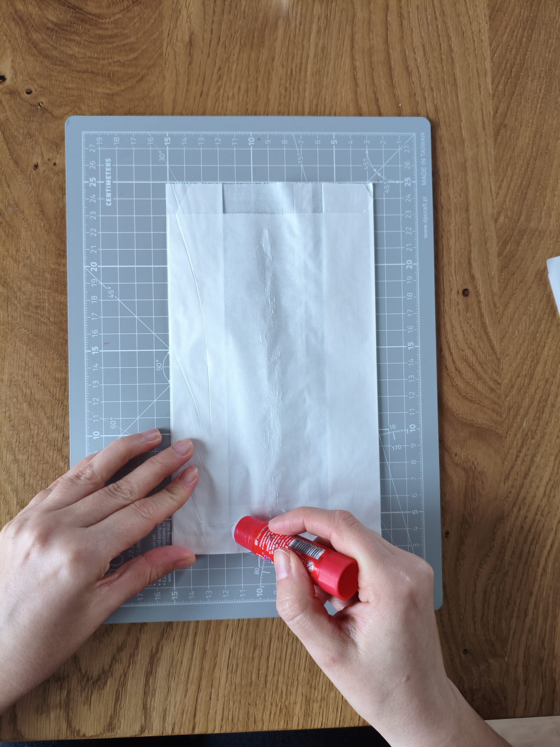 Zdjęcie przedstawiające dłonie klejące papierową torebkę.