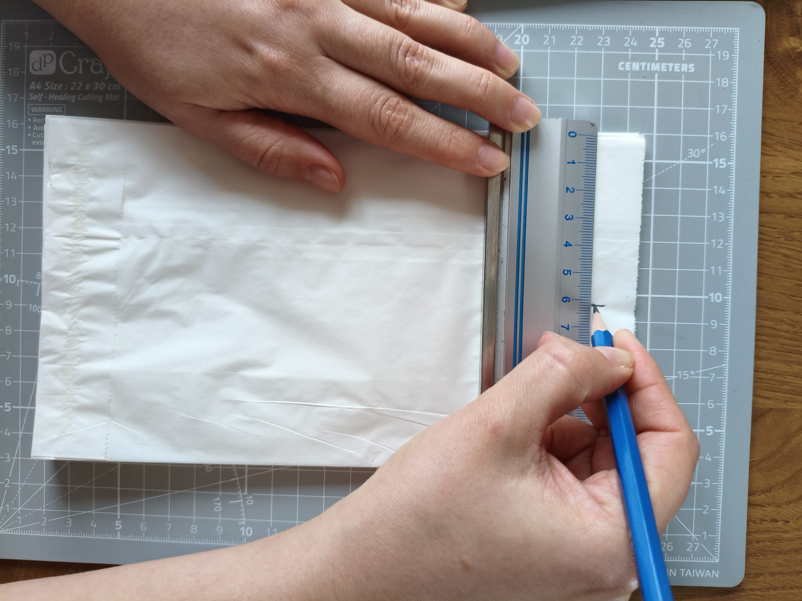 Zdjęcie przedstawiające dłonie odrysowujące linie na papierowej torebce.