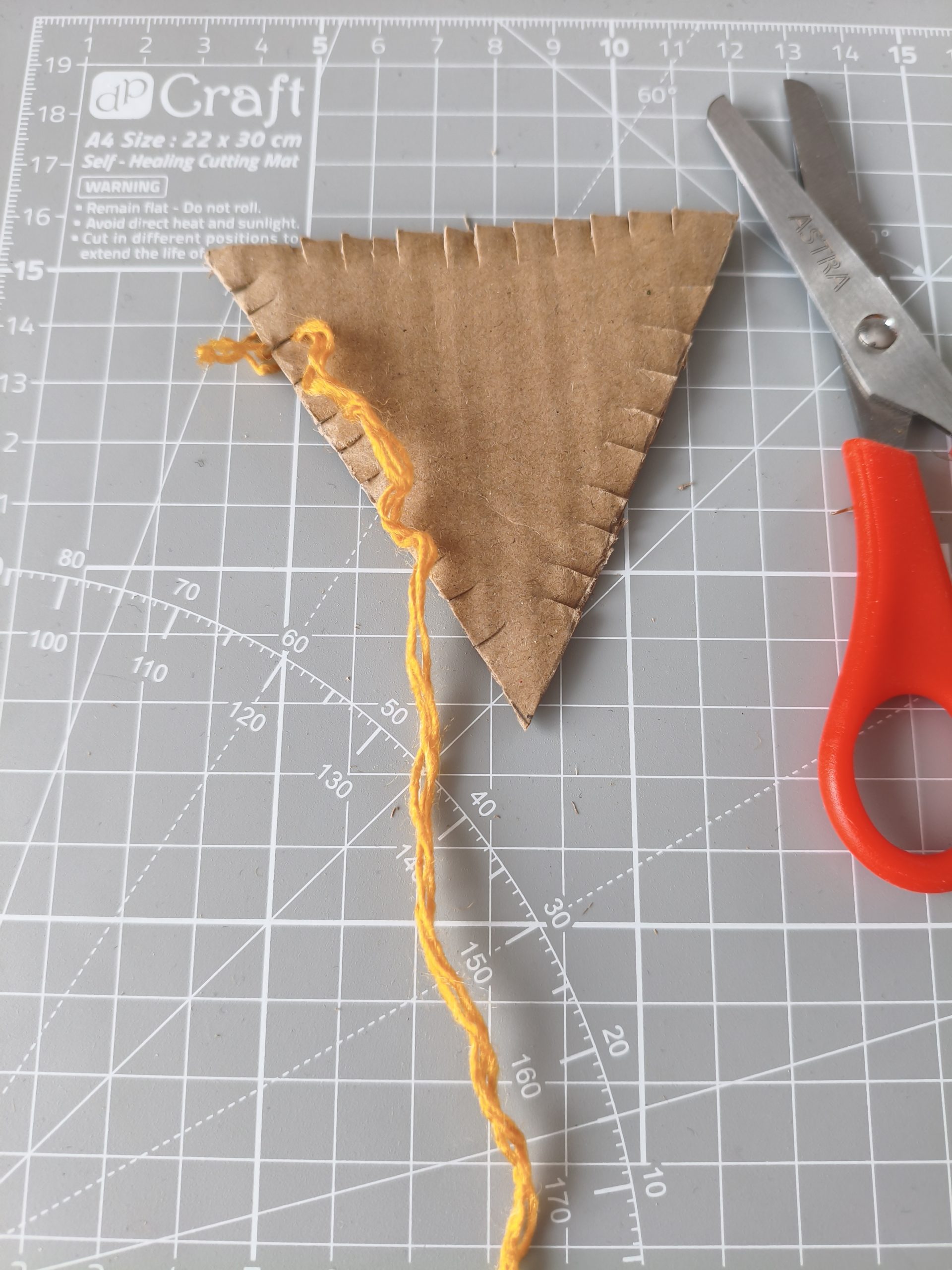 Głowa lisa wycięta z kartonu z kawałkiem włóczki na boku.