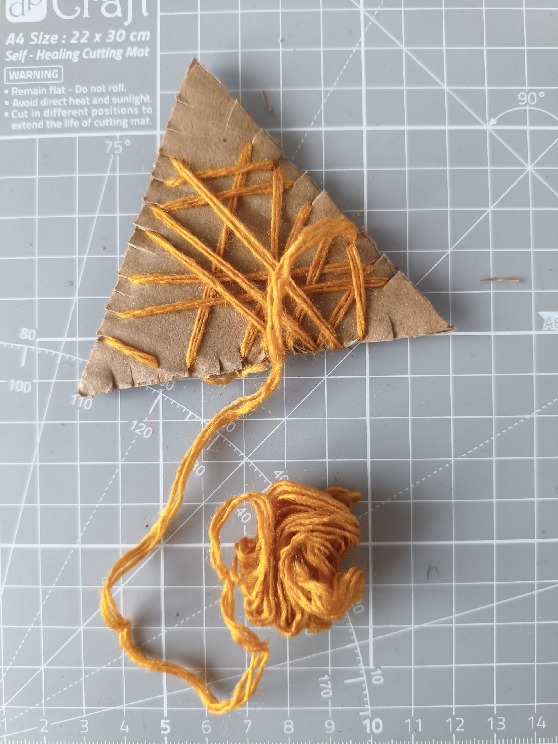 Głowa lisa wycięta z kartonu opleciona częściowo włóczką.