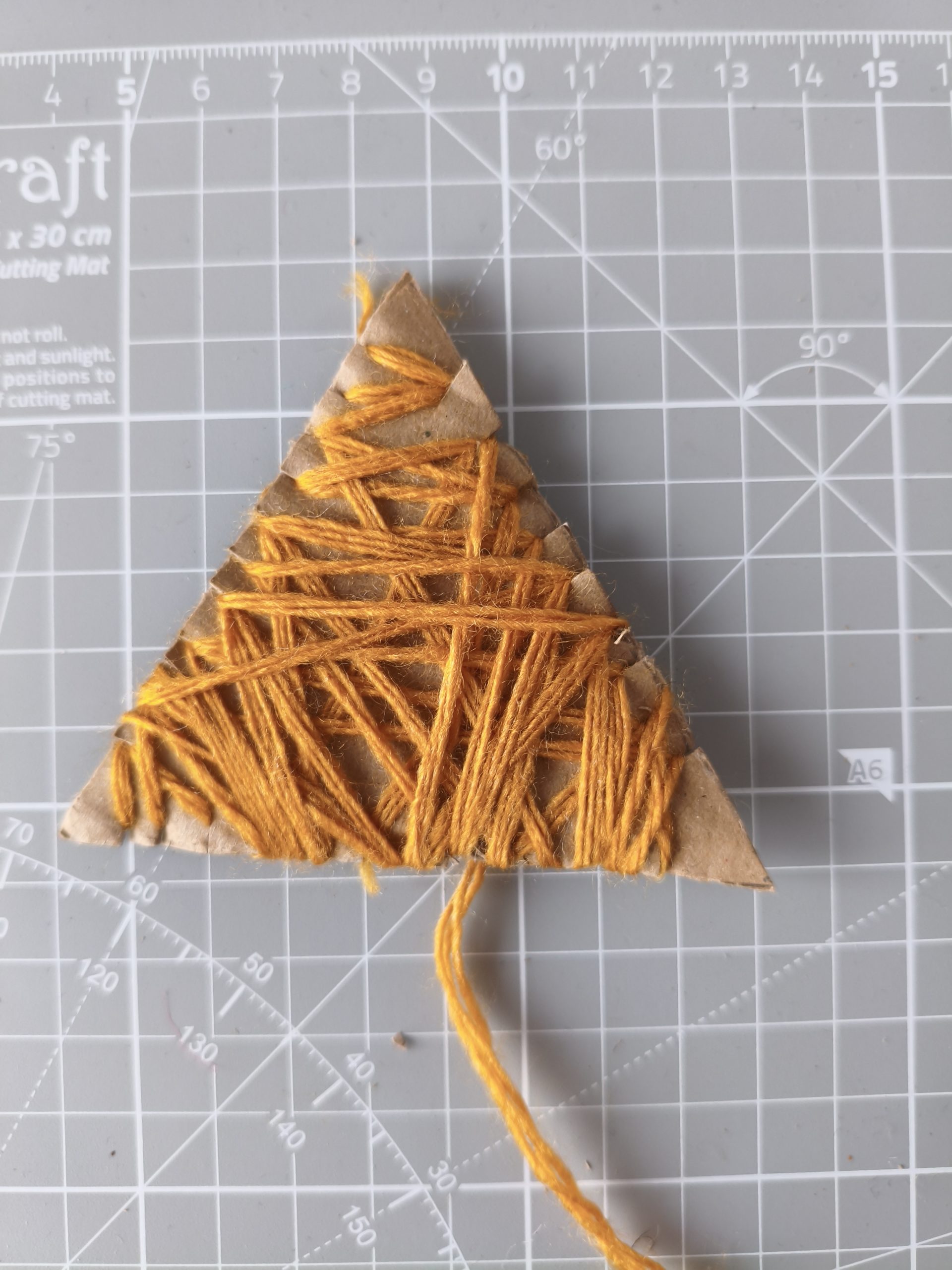 Głowa lisa wycięta z kartonu opleciona częściowo włóczką.