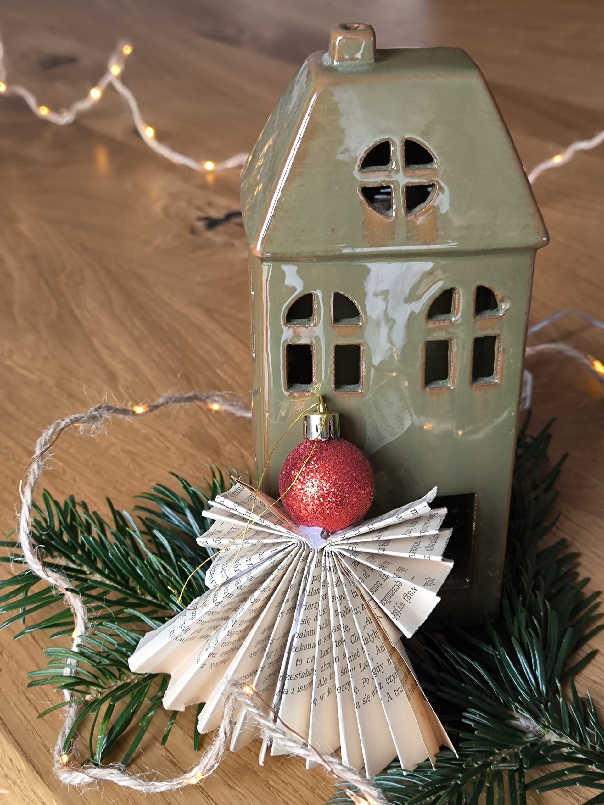 Aniołek wykonany z papieru oparty o ceramiczny domek.