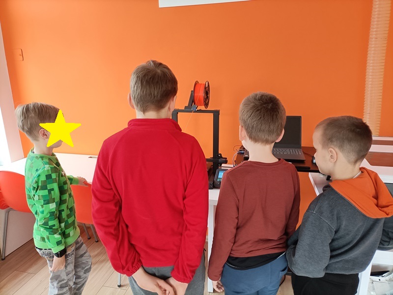 Chłopcy obserwujący pracę drukarki 3D.