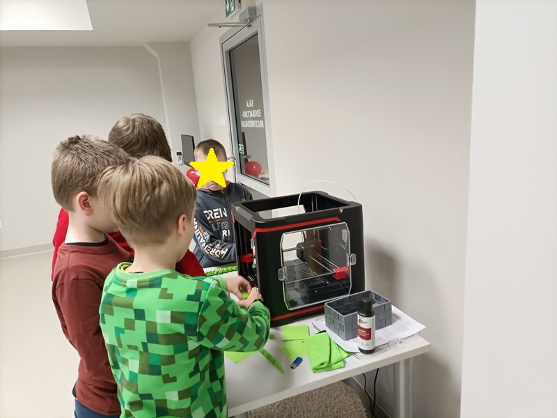 Chłopcy obserwujący pracę drukarki 3D.