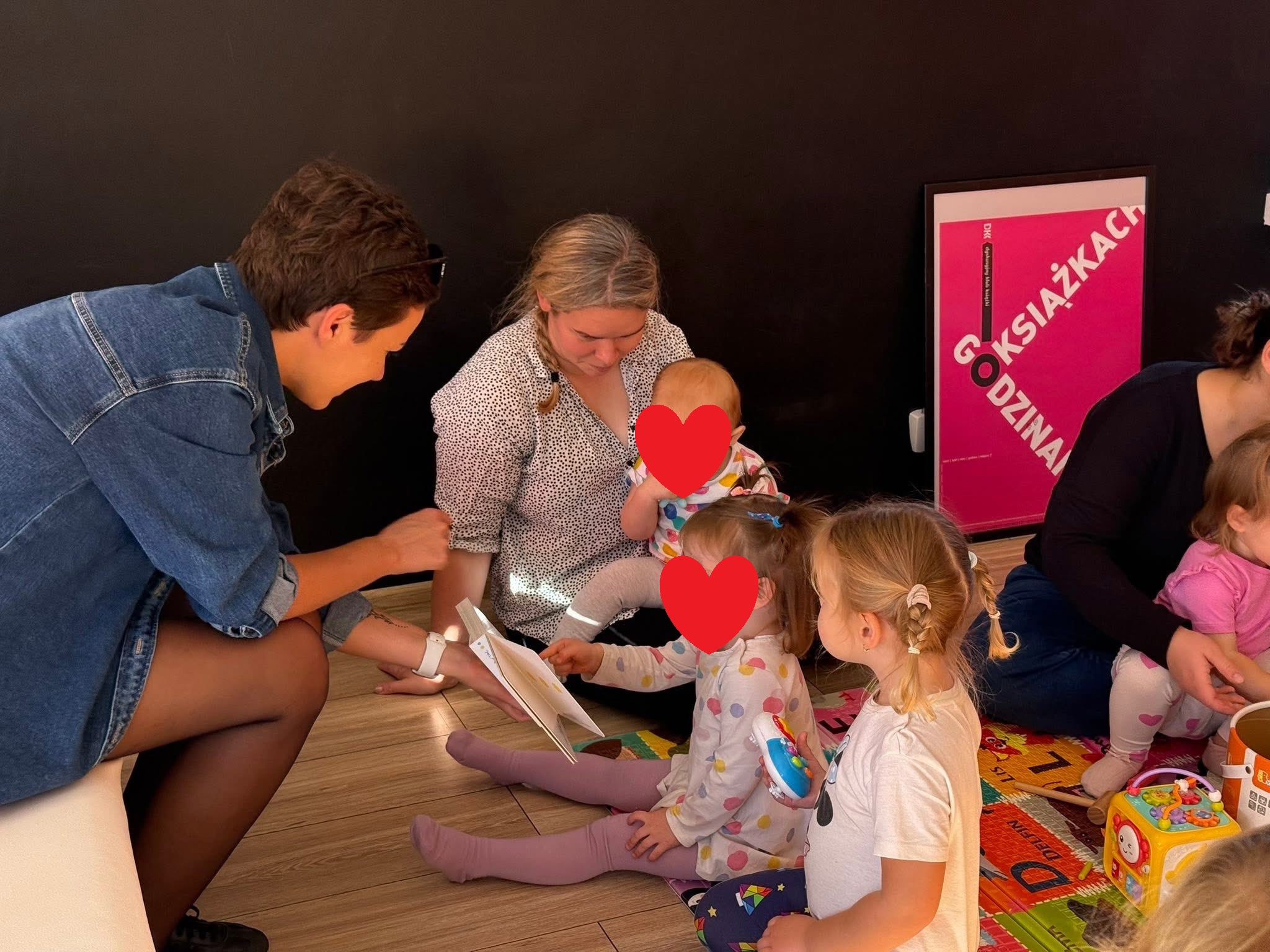 Dzieci wskazujące palcami na obrazki w trakcie czytania ksiażki.