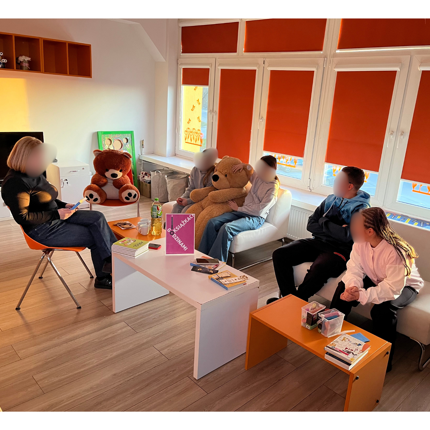 Grupa osób siedzi na kanapach.