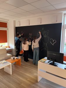 Trójka dzieci maluje na czarnej tablicy kredowej.