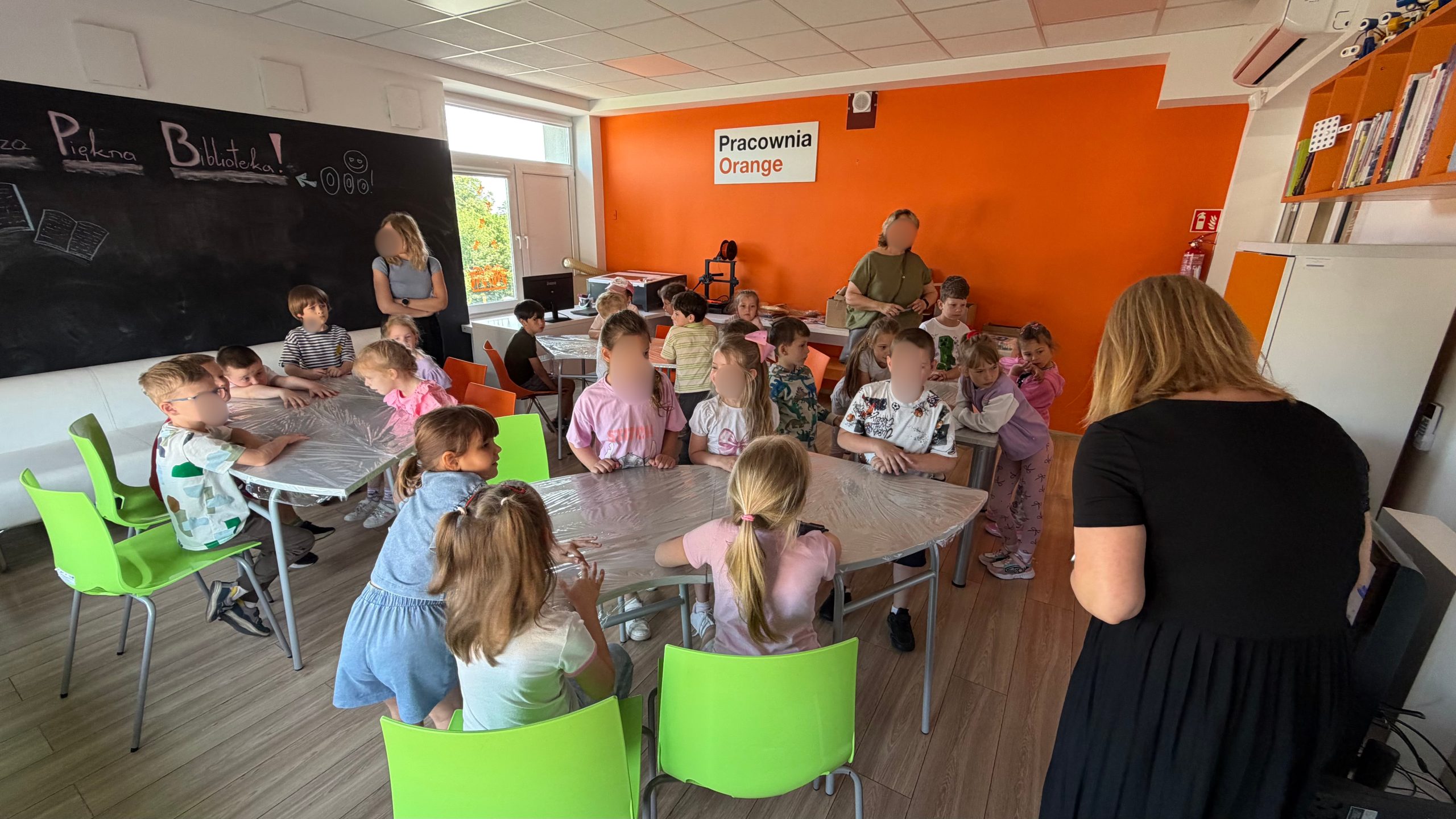 Dzieci siedzą przy stołach w Pracowni Orange