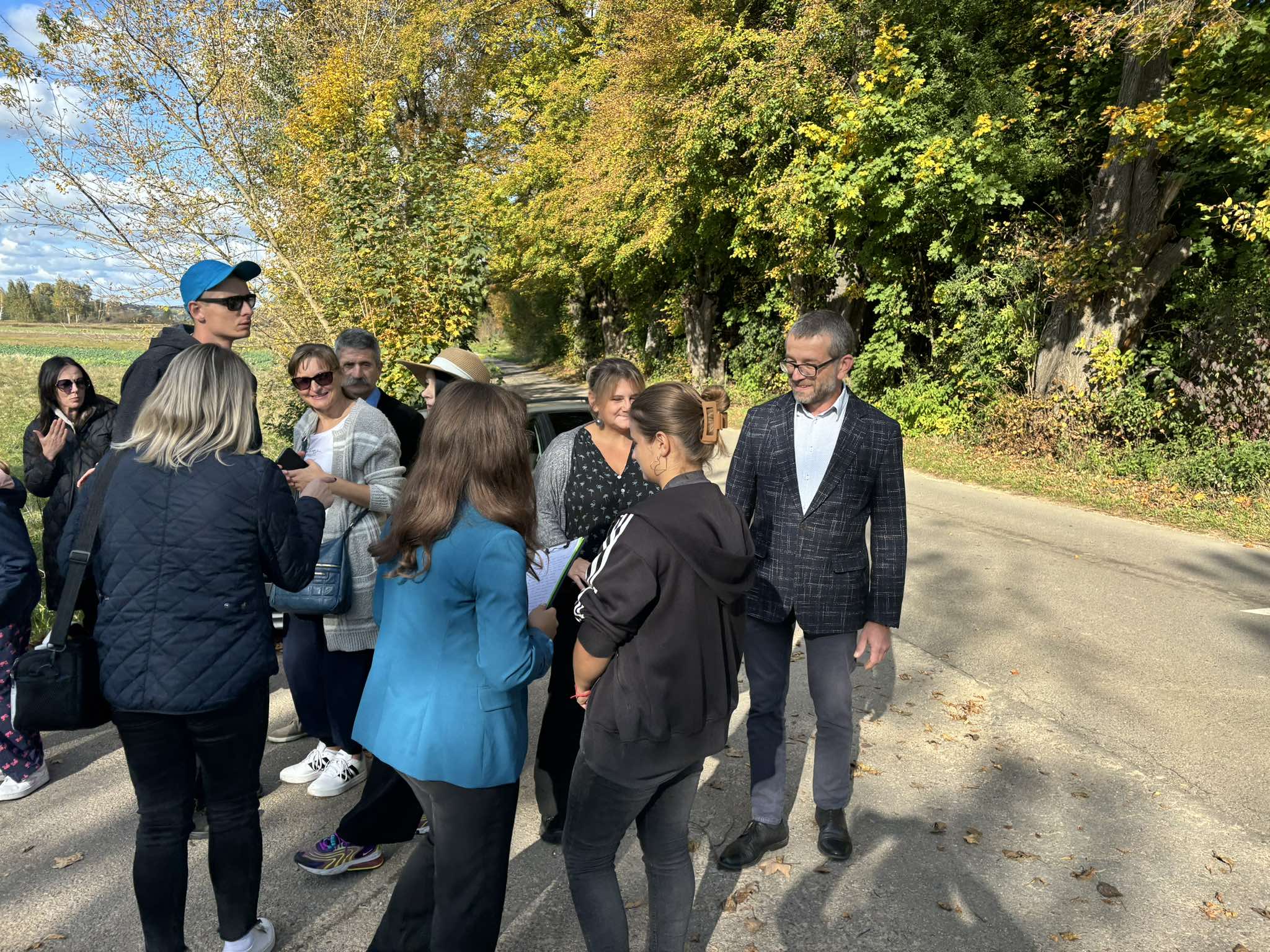 grupa osób na drodze przy lesie