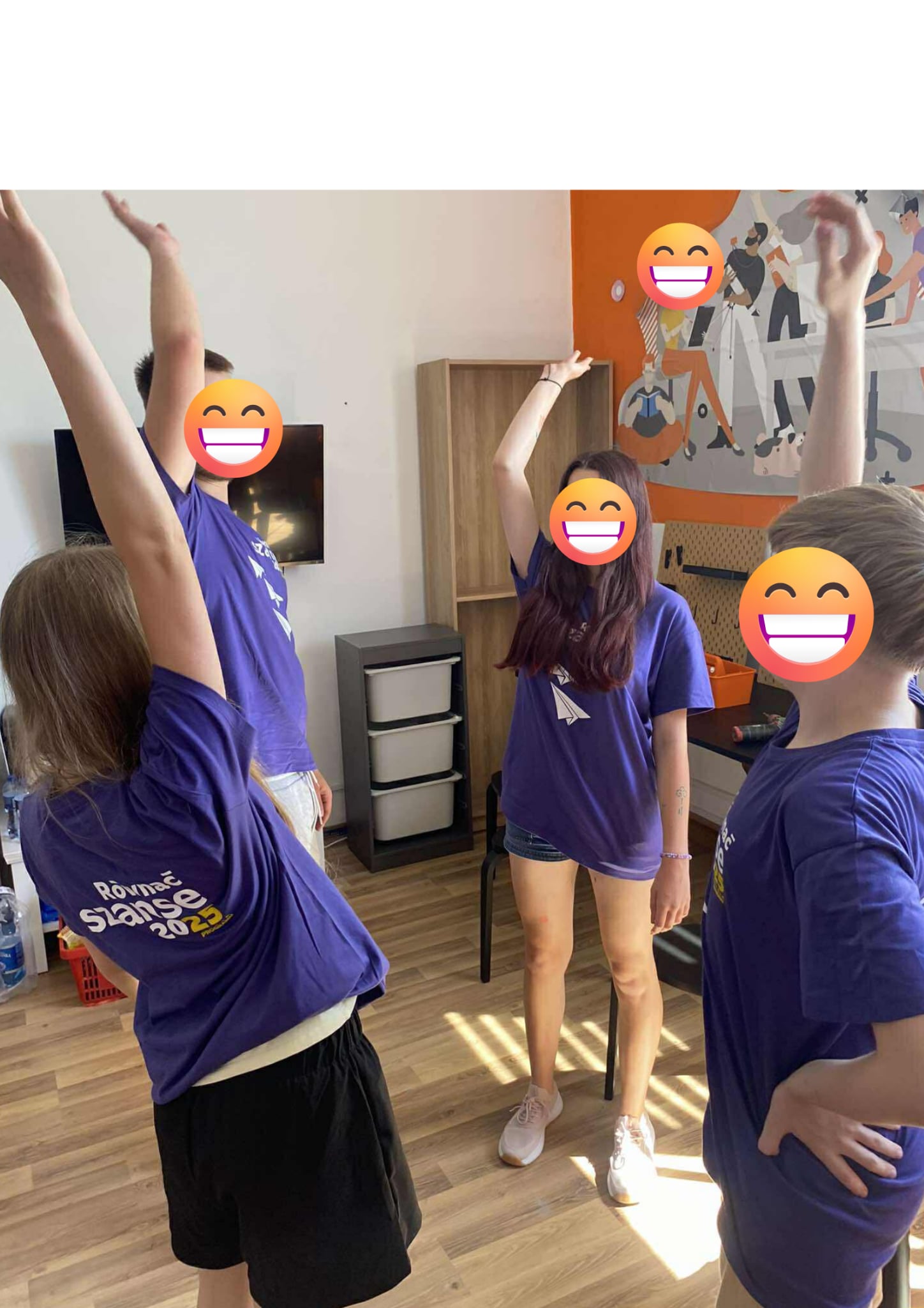 Czwórka młodych osób z uniesionymi rękami w pomieszczeniu pracowni Orange