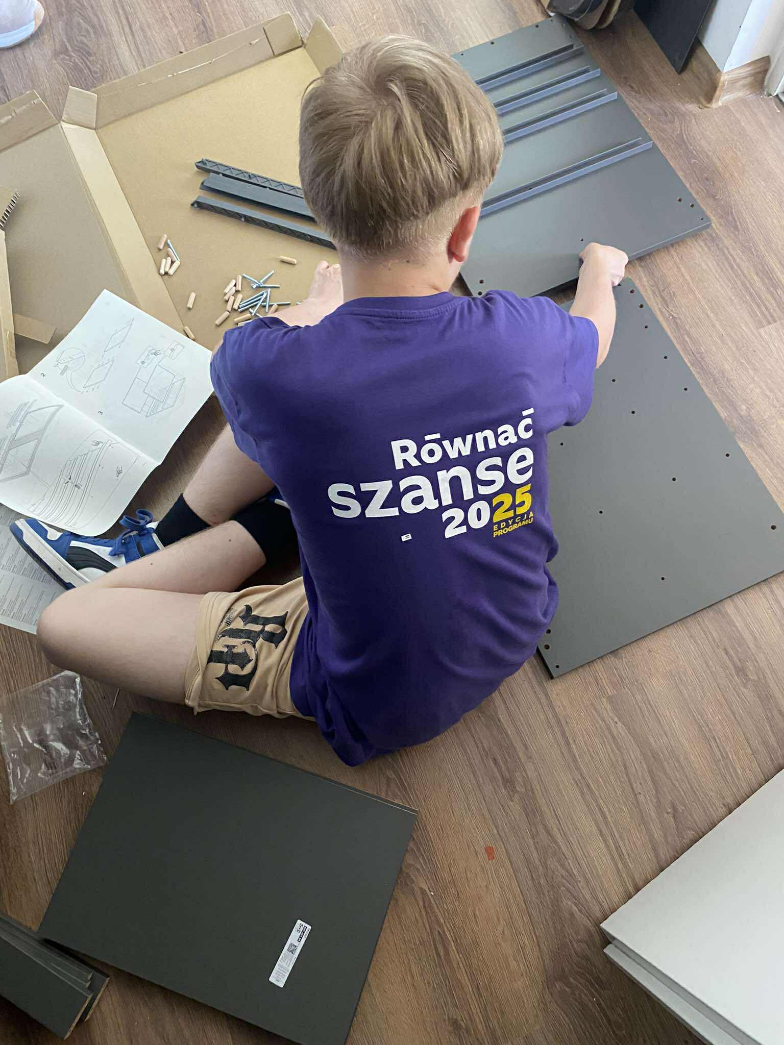 zdjęcie- chłopiec pomagający składać meble w pracowni