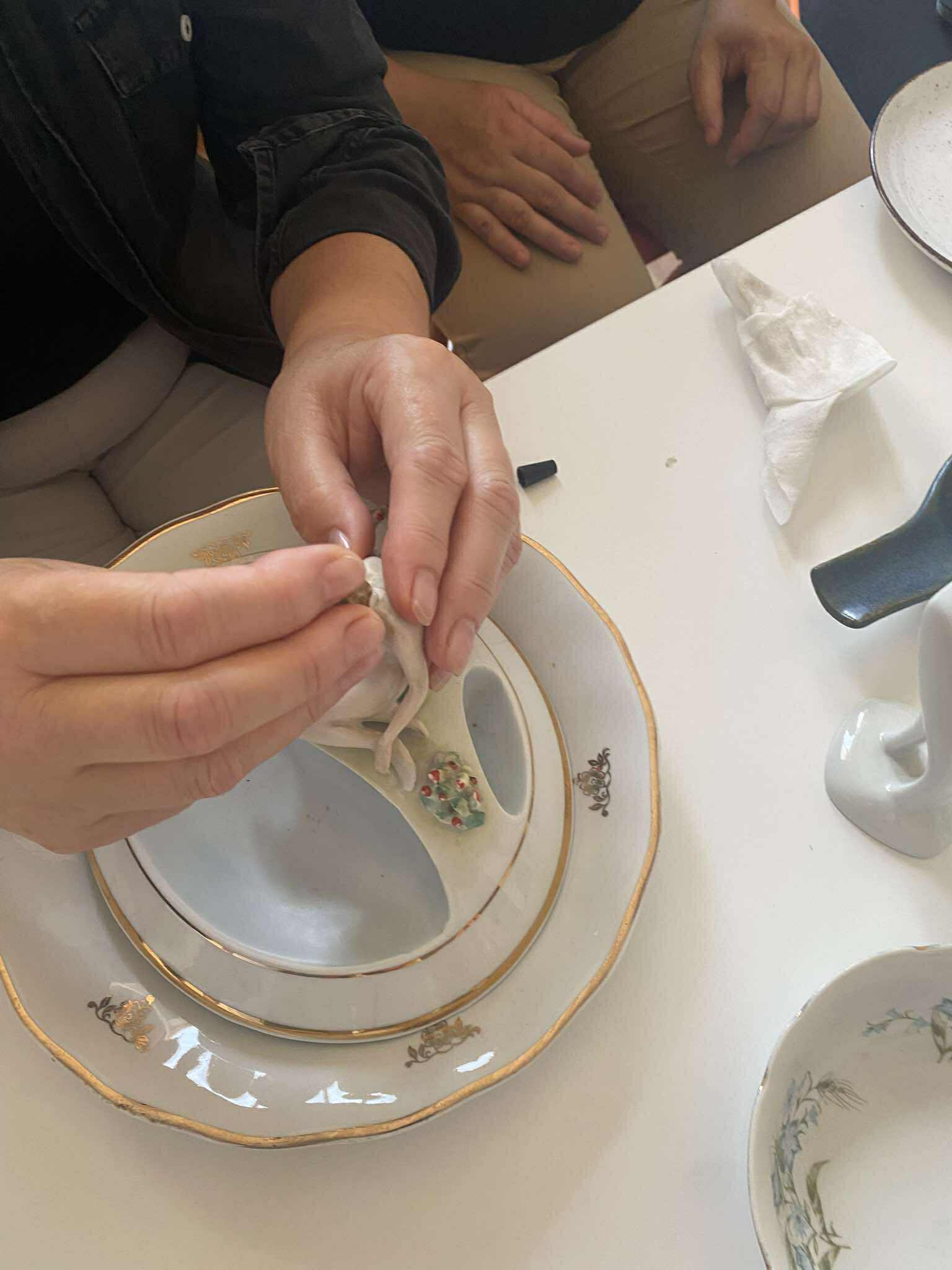 ręce kobiety formujące rzeźbę ze starej porcelany