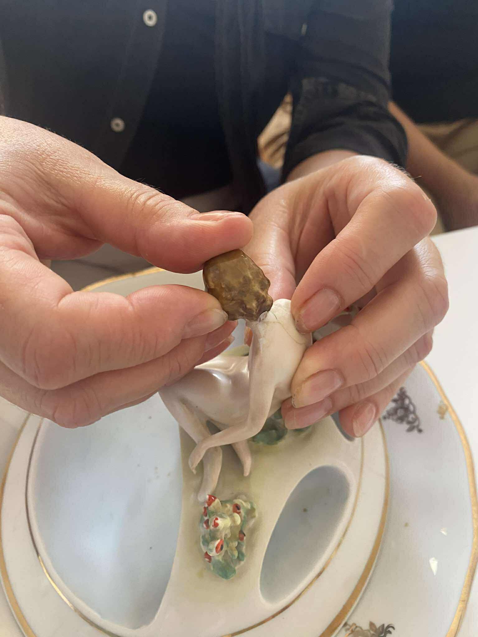 ręce kobiety formujące rzeźbę ze starej porcelany