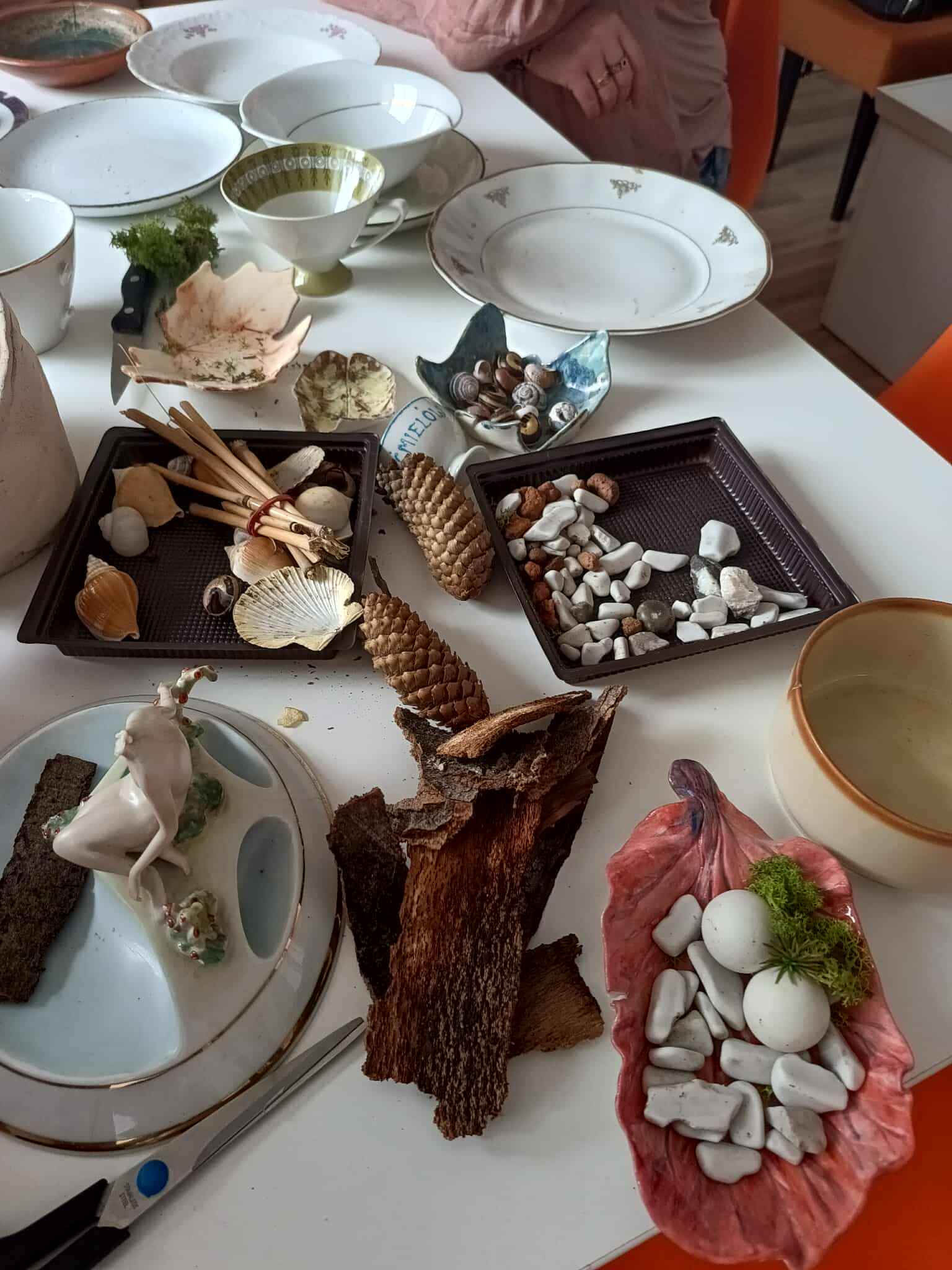 stół warsztatowy, a na nim porcelana, szyszki mech, materiały plastyczne