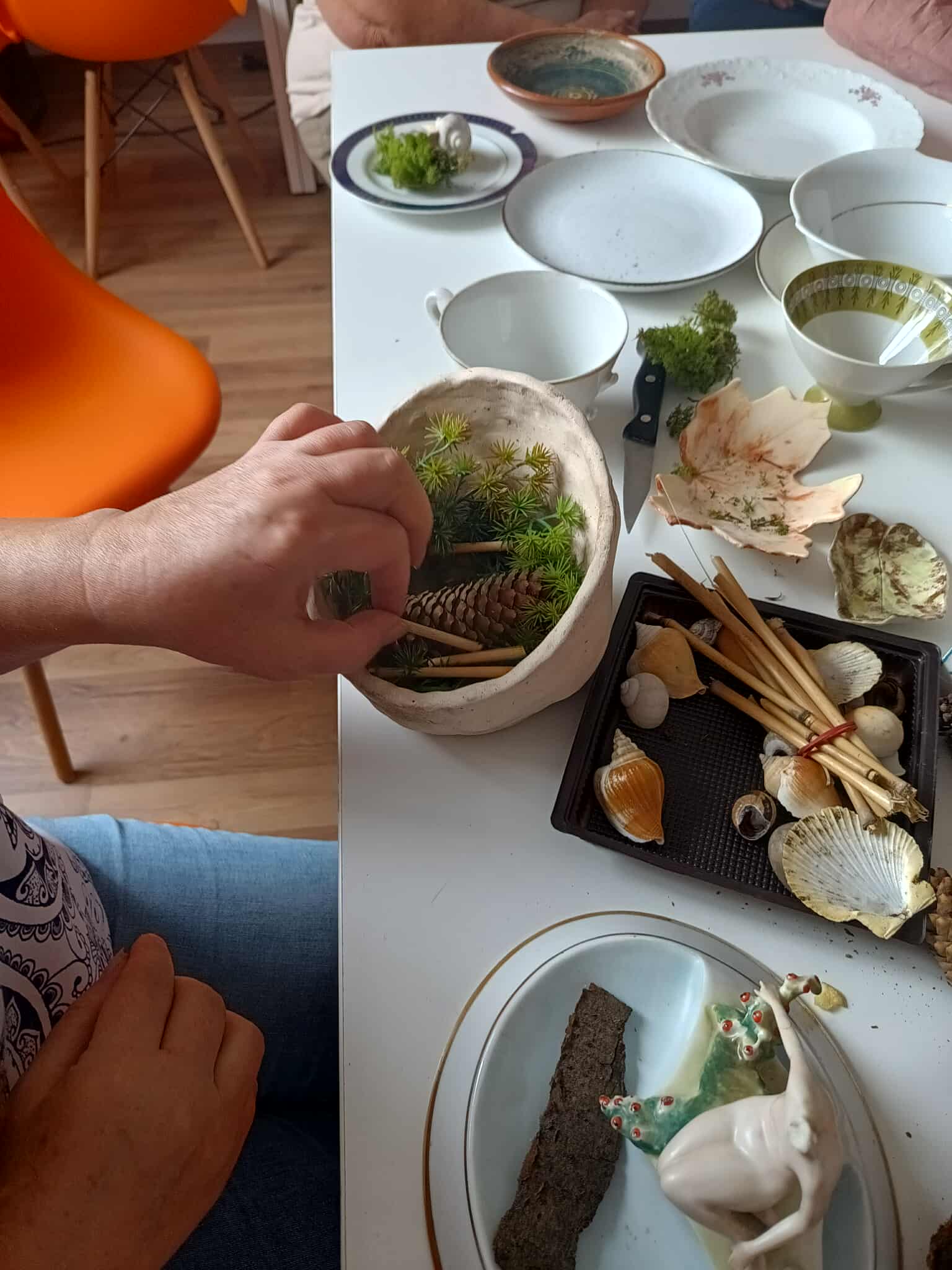 Kobieta formująca na starej porcelanie ozdobę leśną