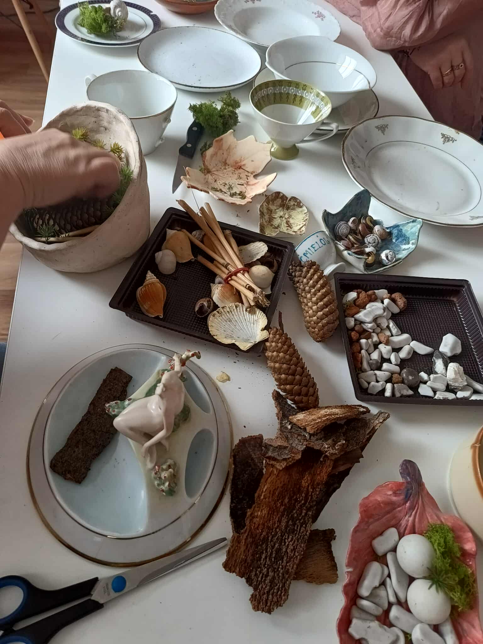 Kobieta formująca na starej porcelanie ozdobę leśną