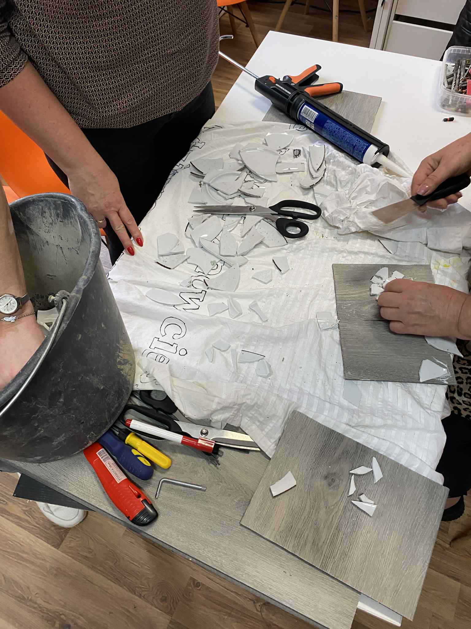 Kobiety wyjmujące na stół potłuczoną porcelanę na mozaiki