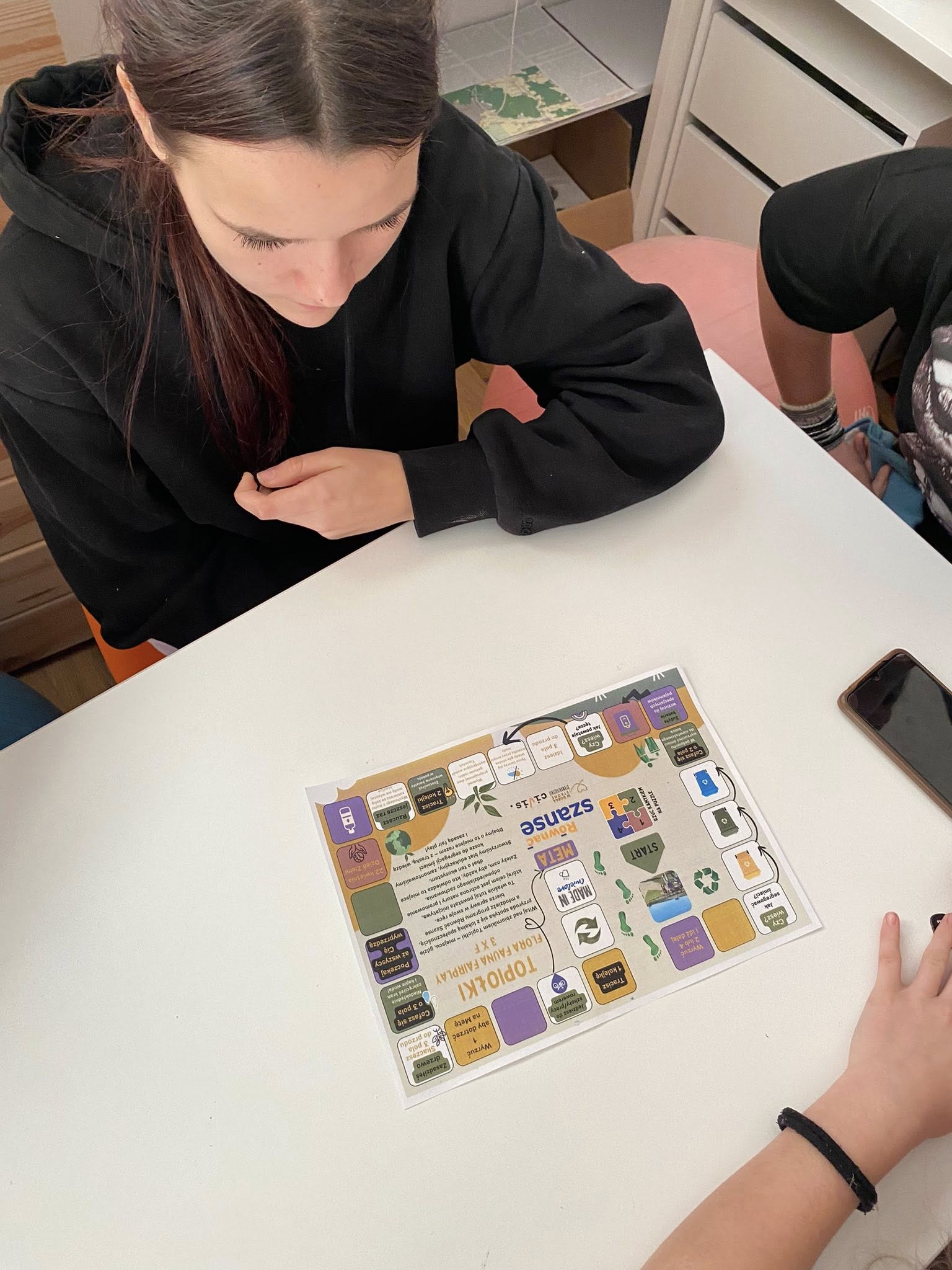 zdjęcie dziewczyny przy stole patrzącej na ulotkę