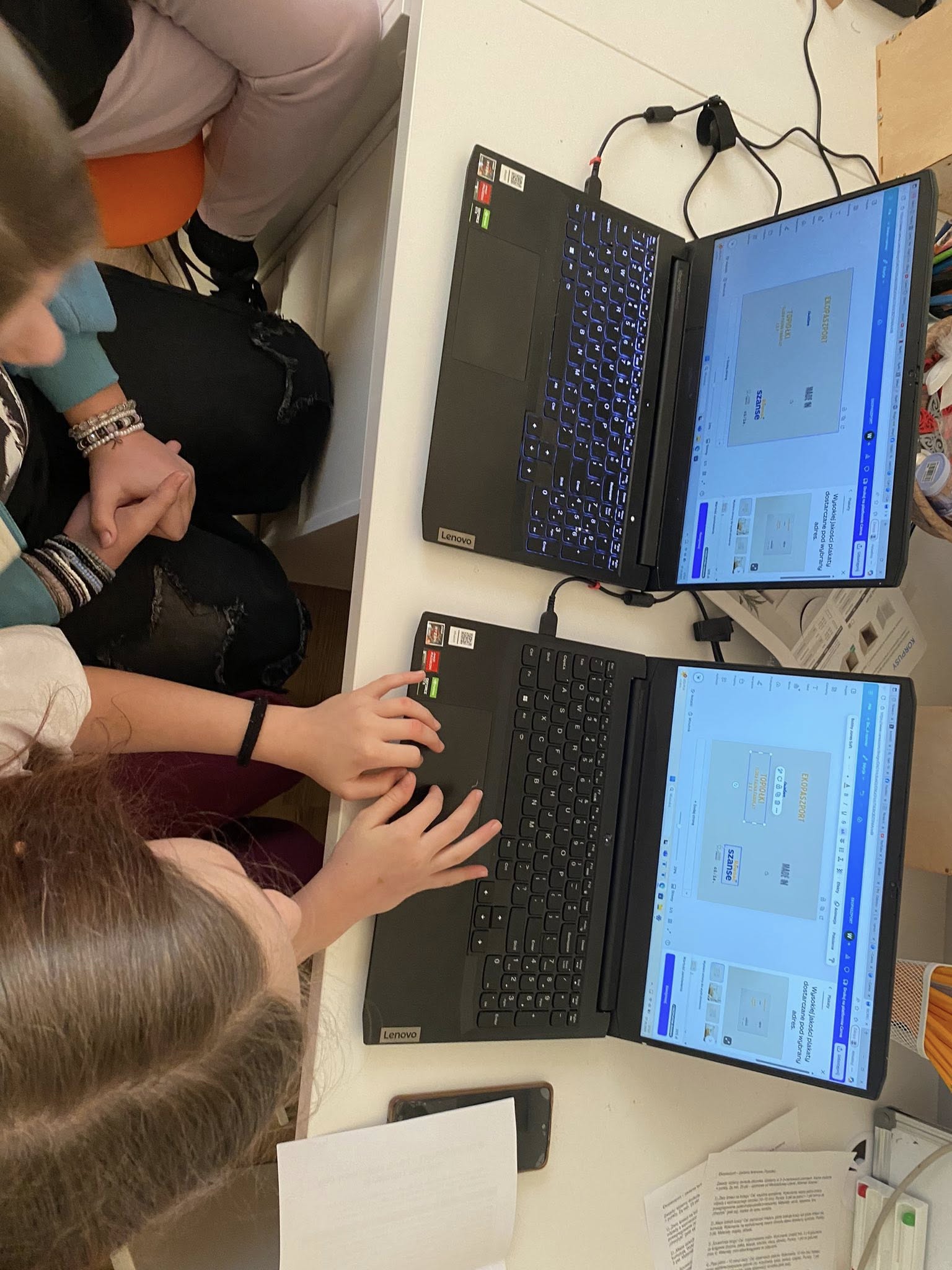 na zdjęciu dwa laptopy, przy których siedzi młodzież