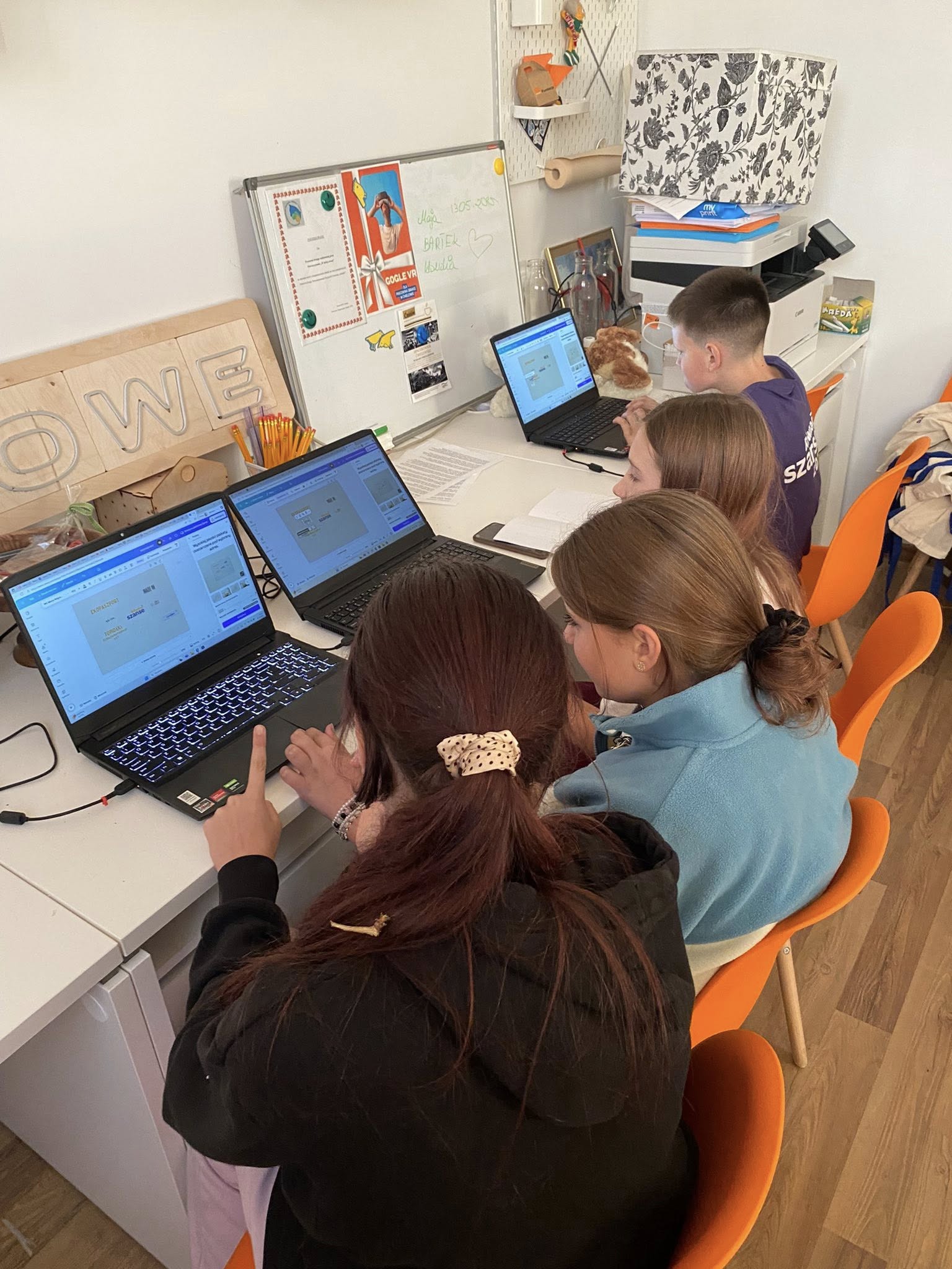 na zdjęciu młodzież siedząca przy laptopach