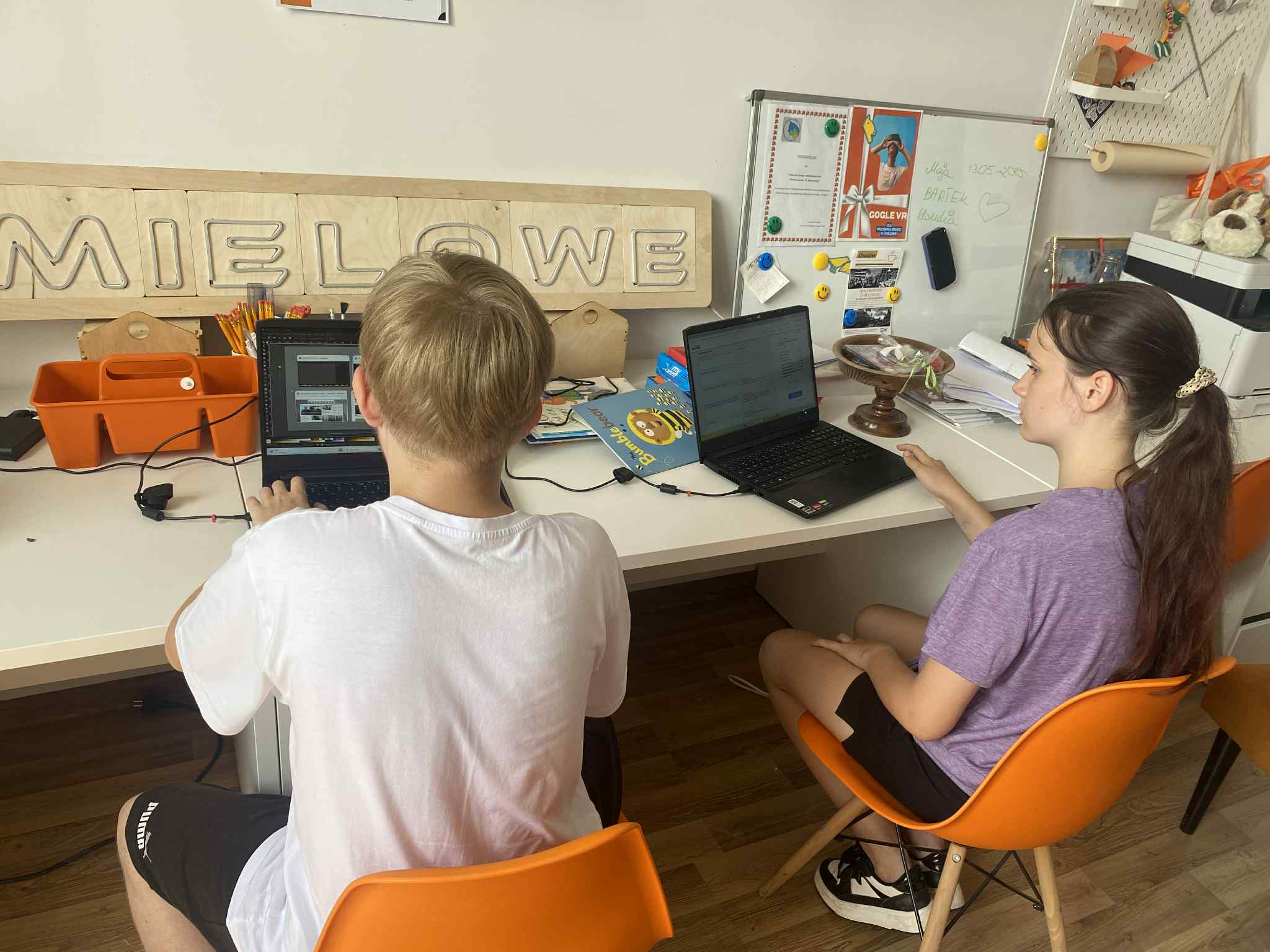 na zdjęciu dwójka dzieci przy laptopach