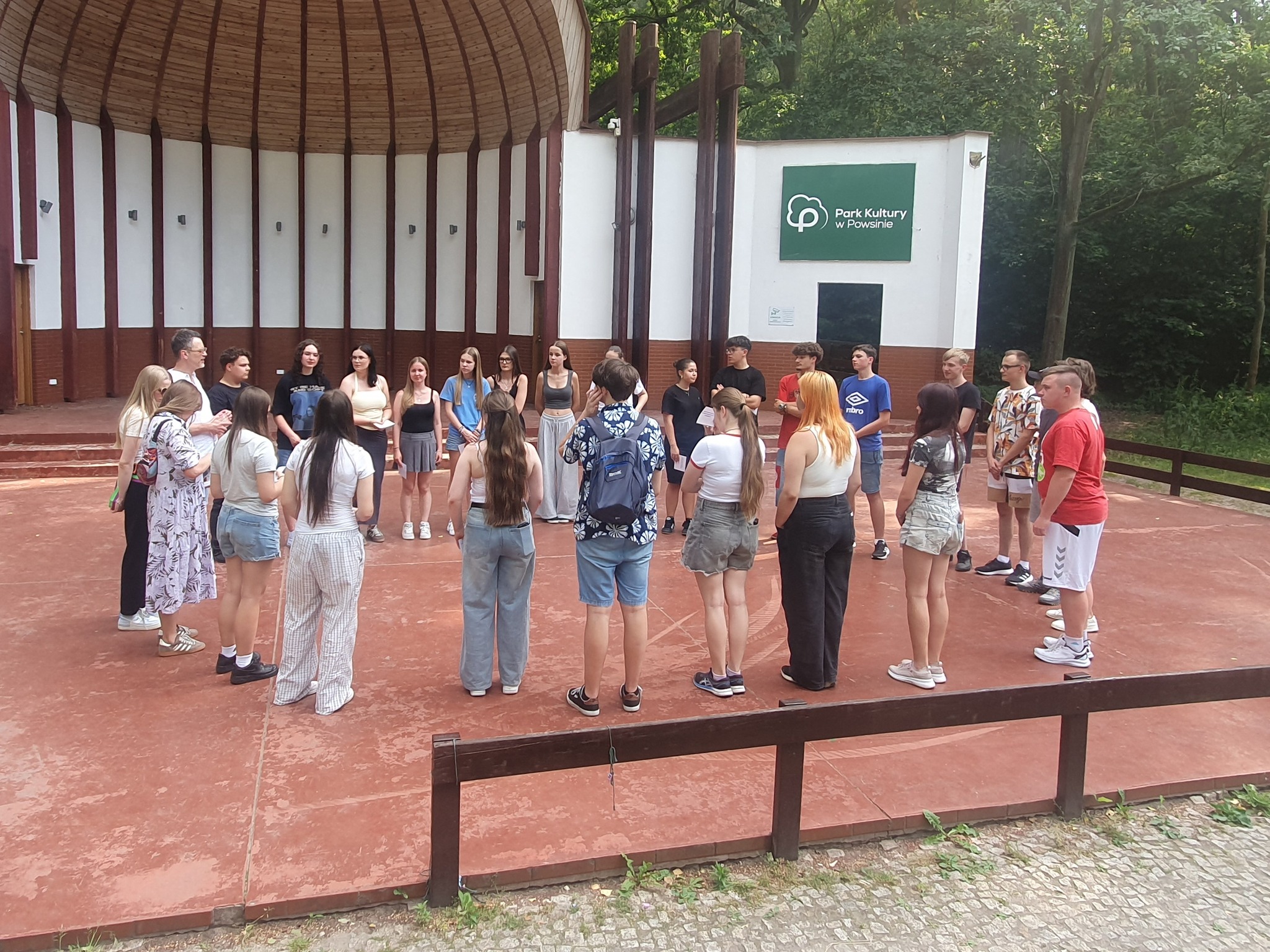 zdjęcie młodzieży stojącej w kółku na zewnątrz