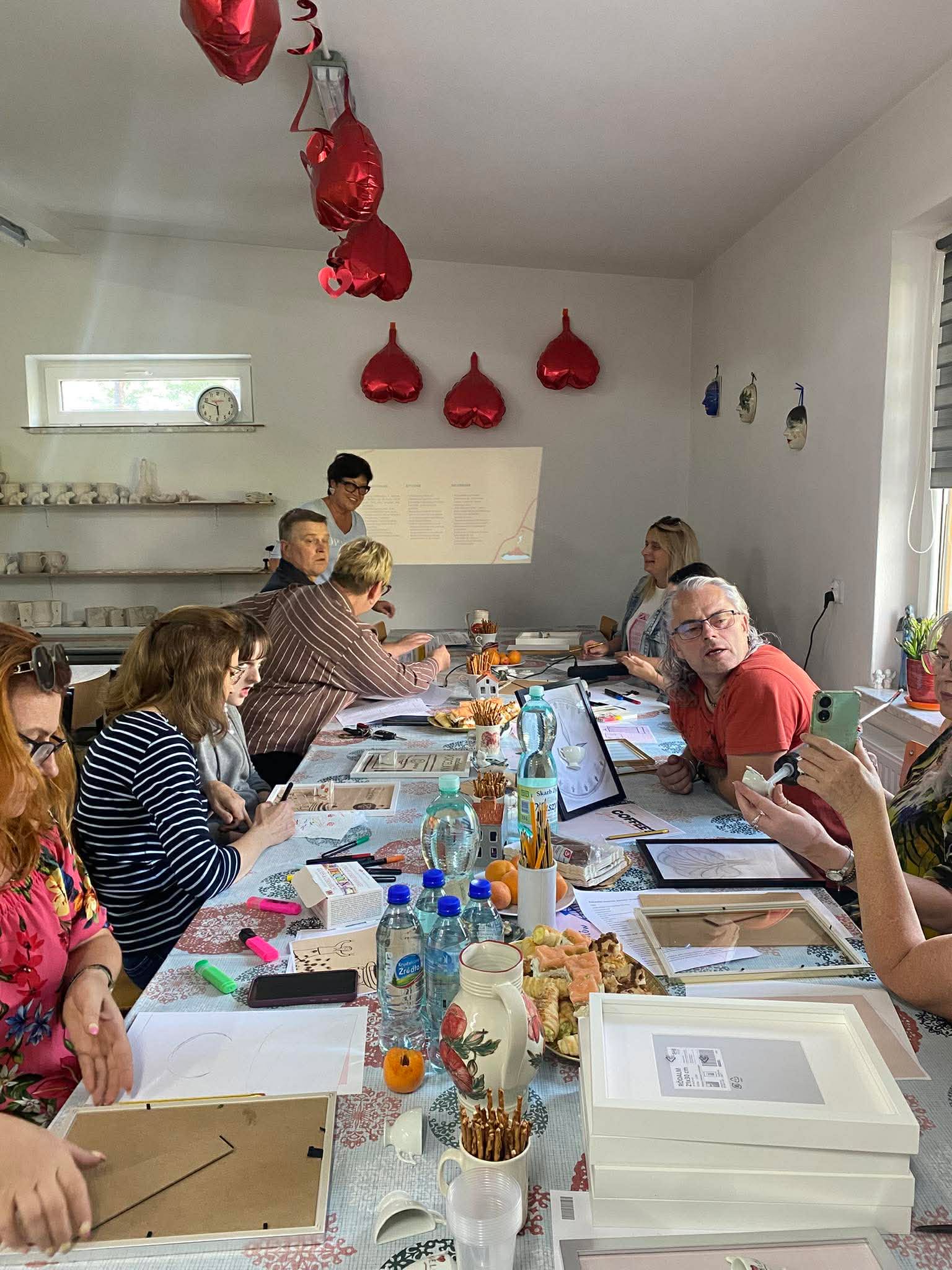 Grupa osób siedzi przy stole podczas warsztatów.