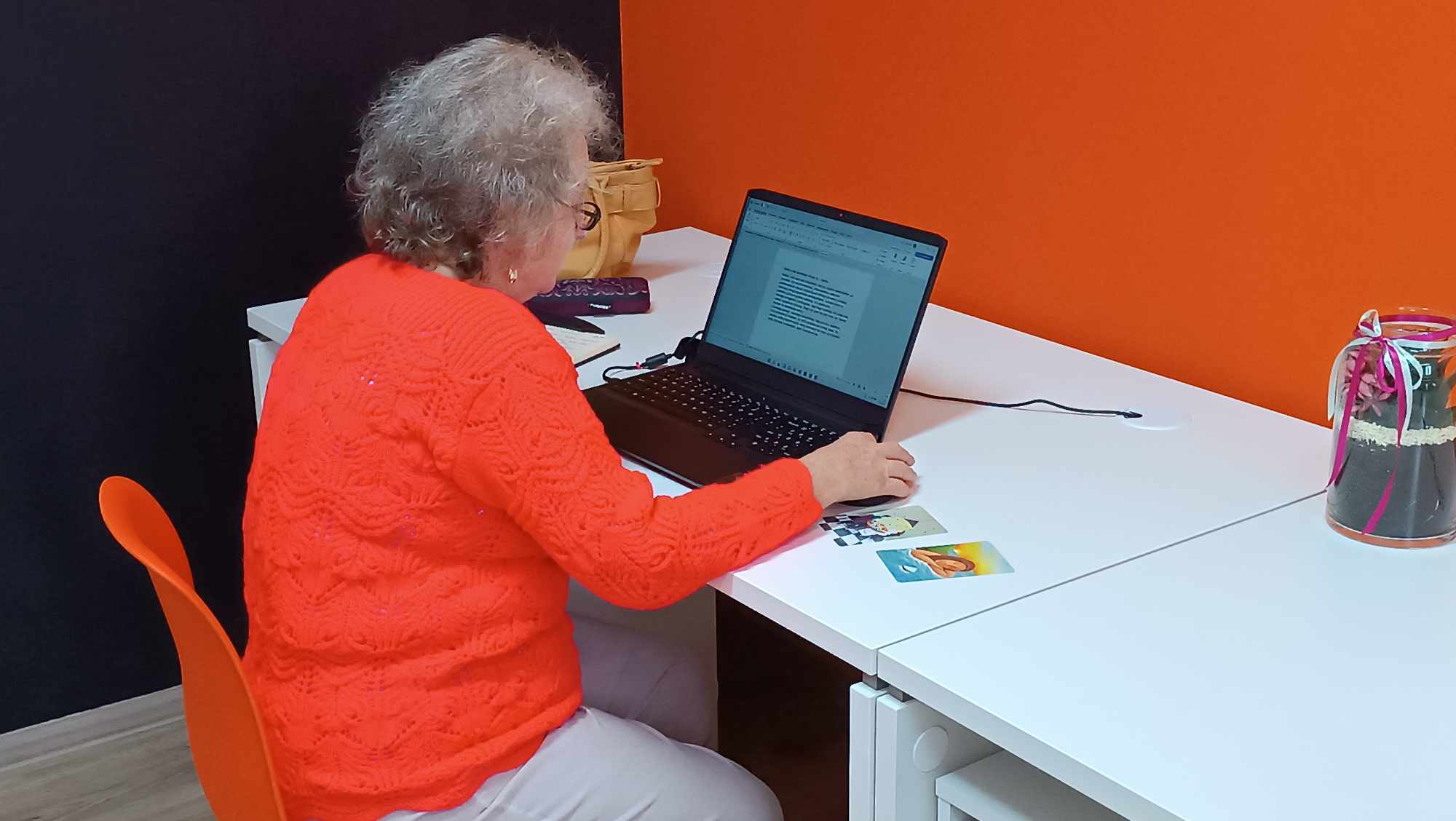 strasza kobieta siedzi przy biurku i korzysta z laptopa