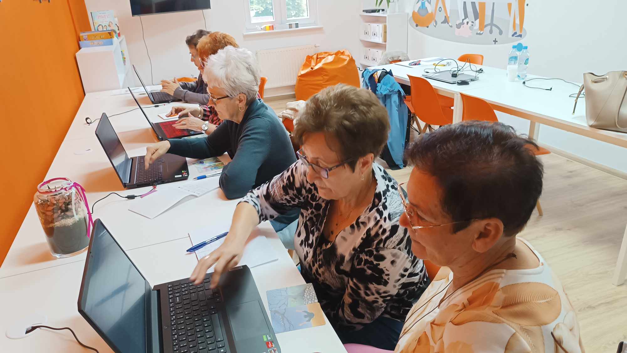 starsze kobiety siedzą przy biurkach uczą się obsługi komputerów