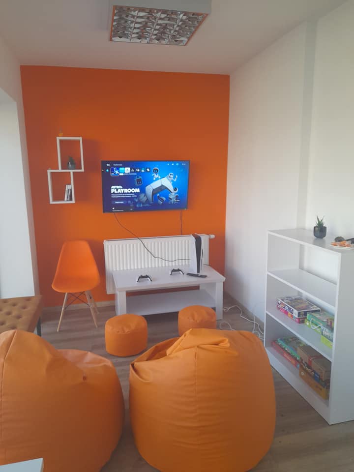 pomieszczenie z pomarańczowymi pufami i ekranem
