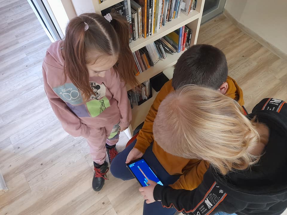 Trójka dzieci gra na telefonie.