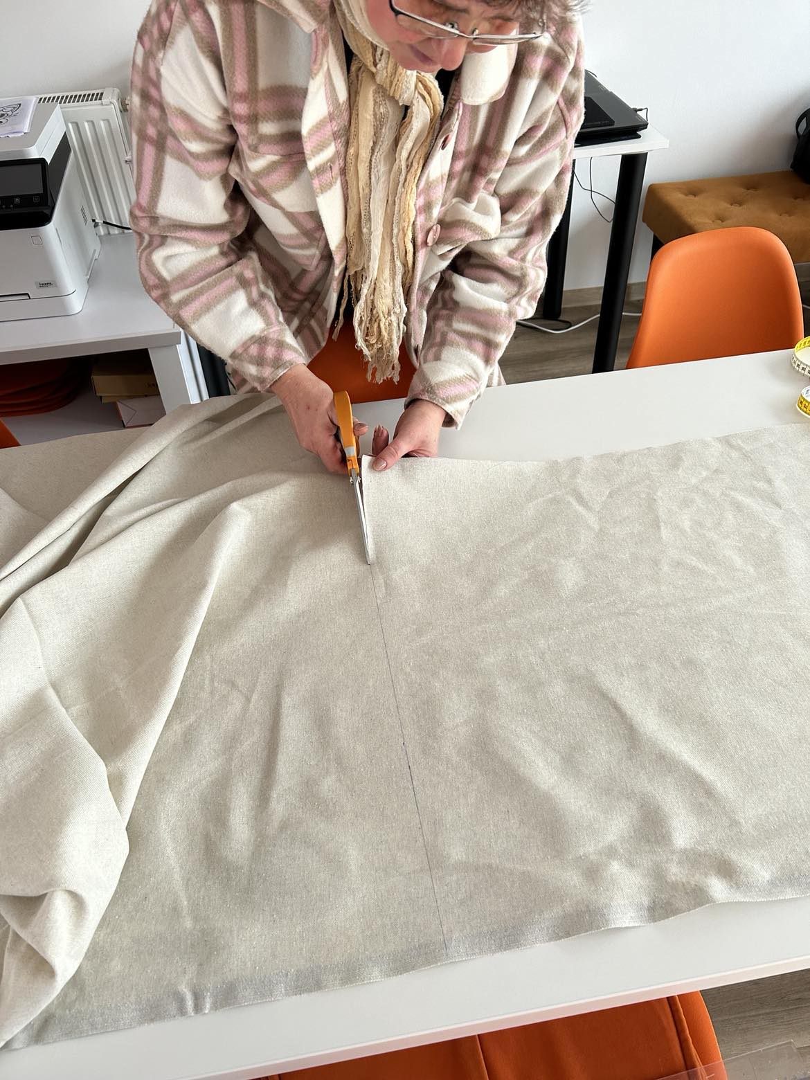 Kobieta tnie materiał nożyczkami.