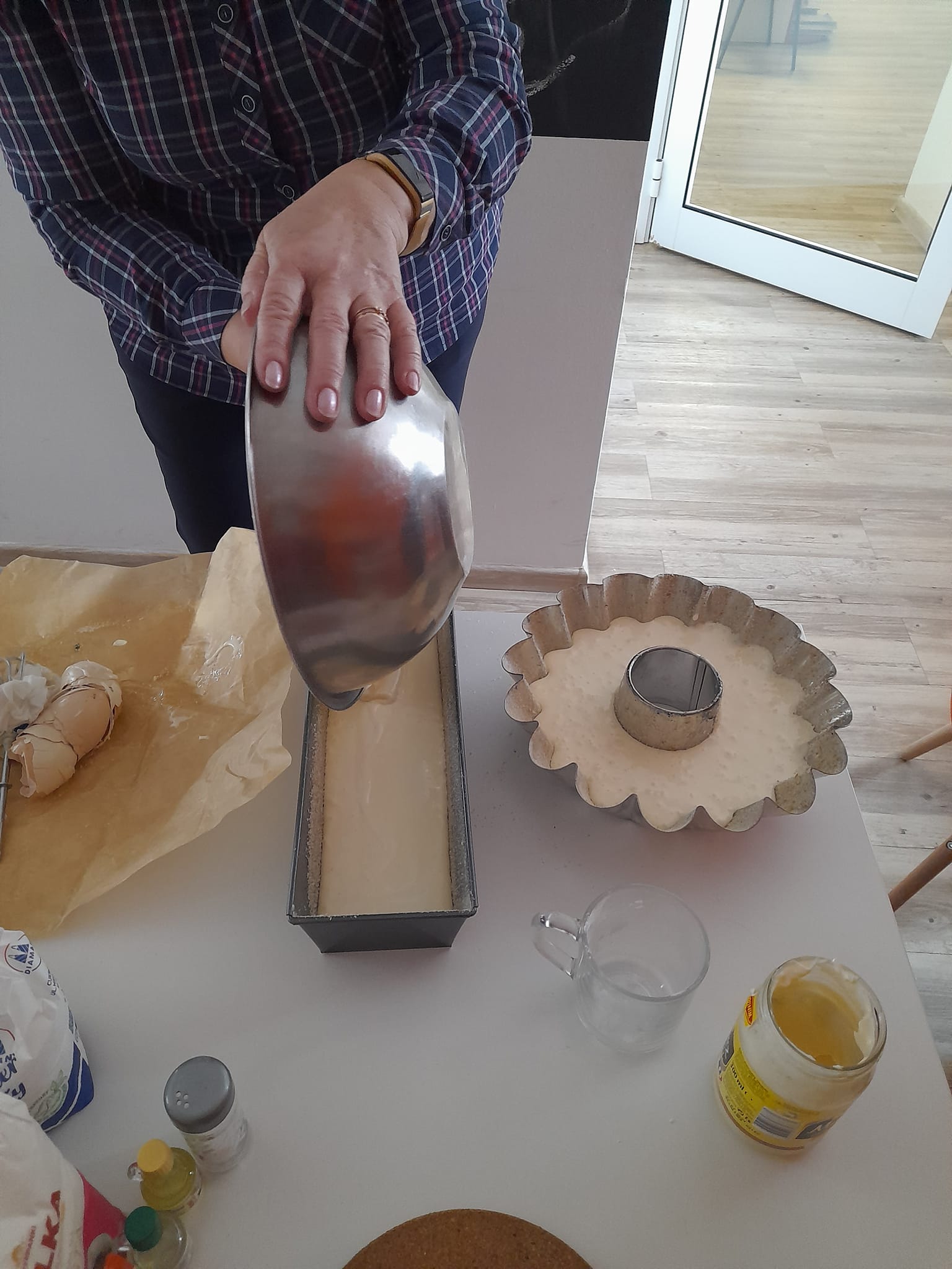 Uczestniczka spotkania wlewa masę do metalowej foremki.