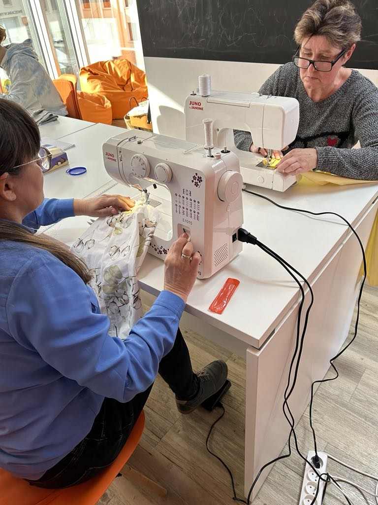 Dwie kobiety siedzące przy maszynie.