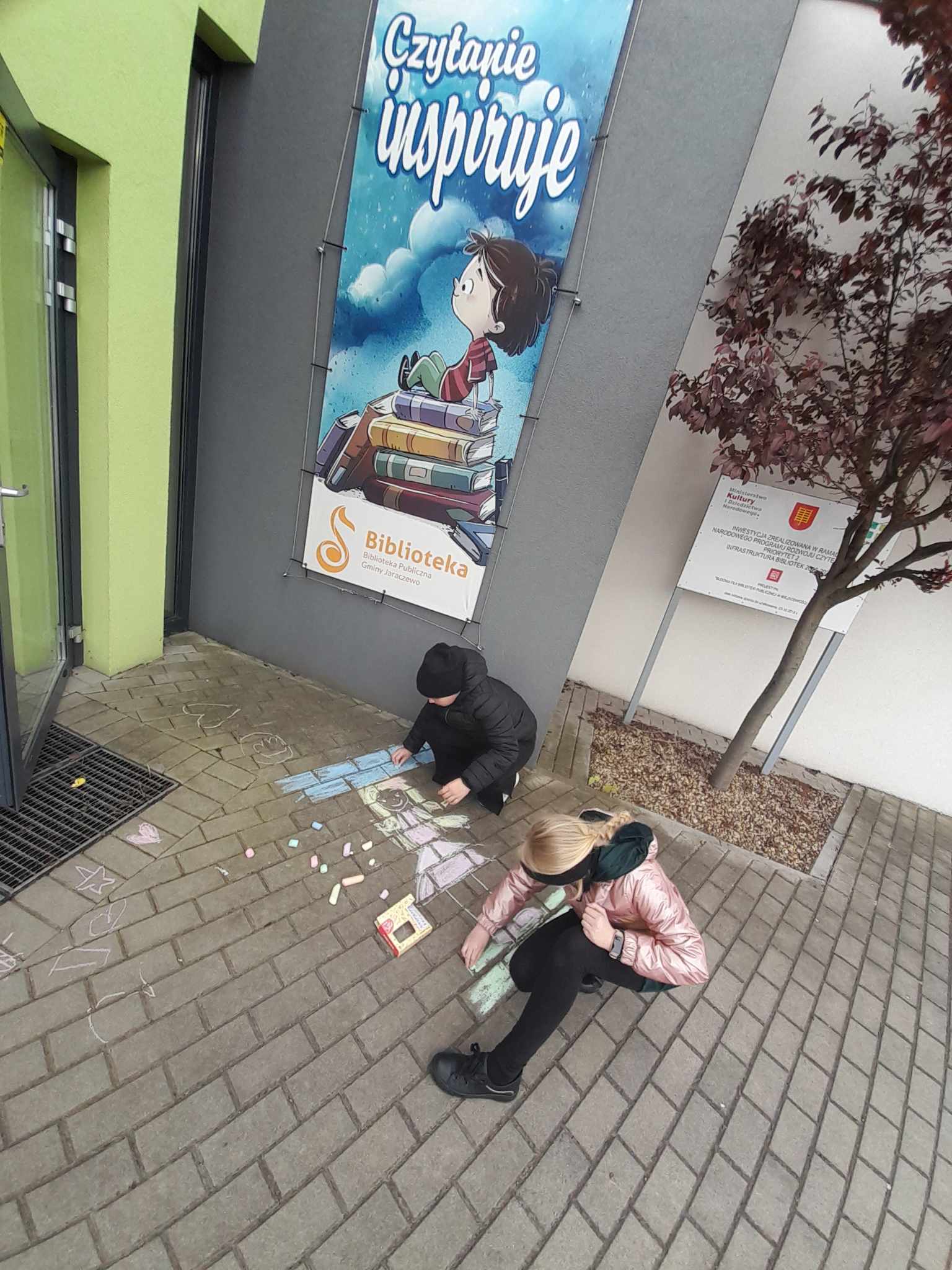 Dwie dziewczynki malujące kredą na chodniku.