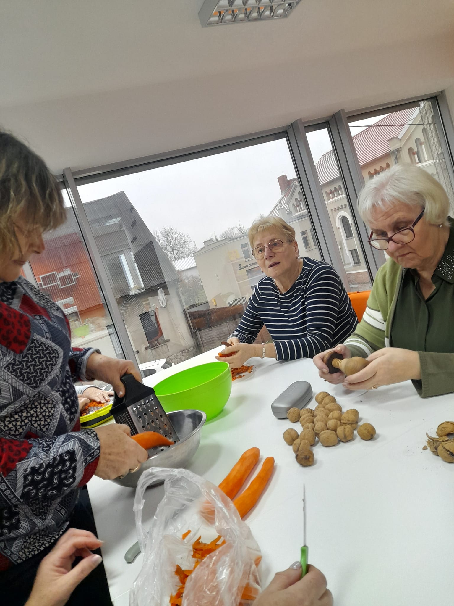 Grupa kobiet siedzi przy stole i przygotowuje składniki na ciasto.