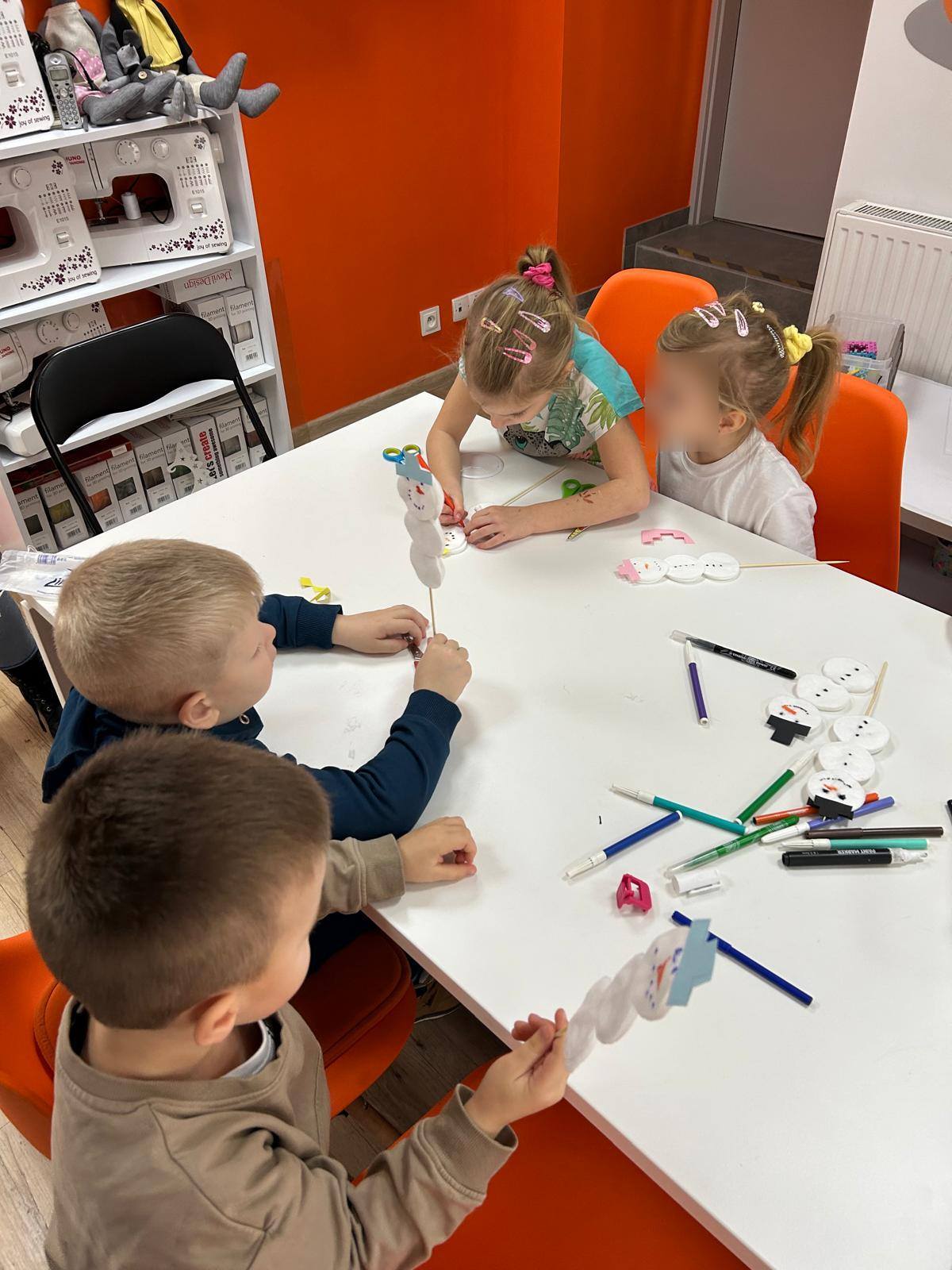 Czwórka dzieci siedzi przy stole i pracuje