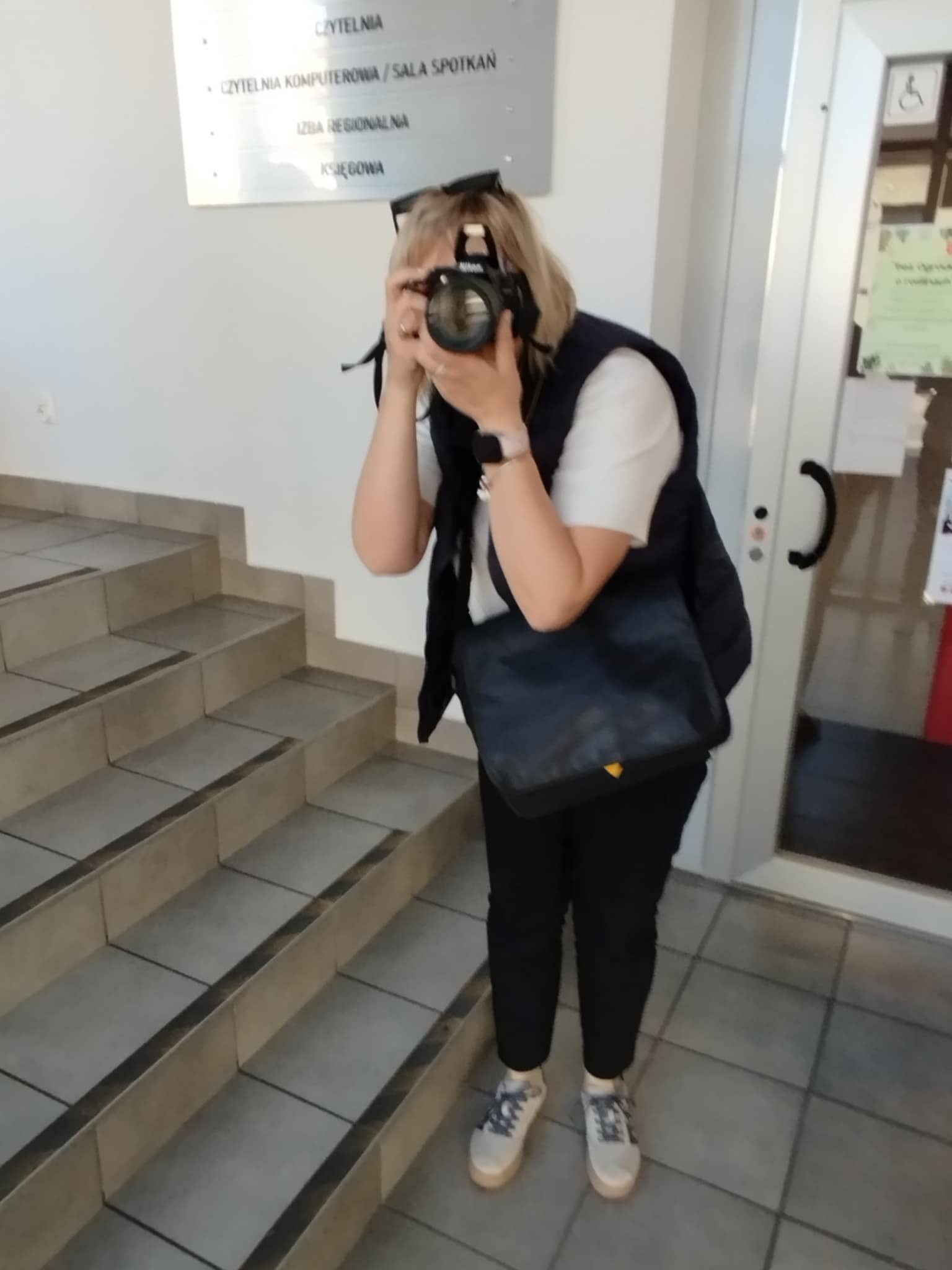 Kobieta z aparatem w dłoni robi zdjęcie.