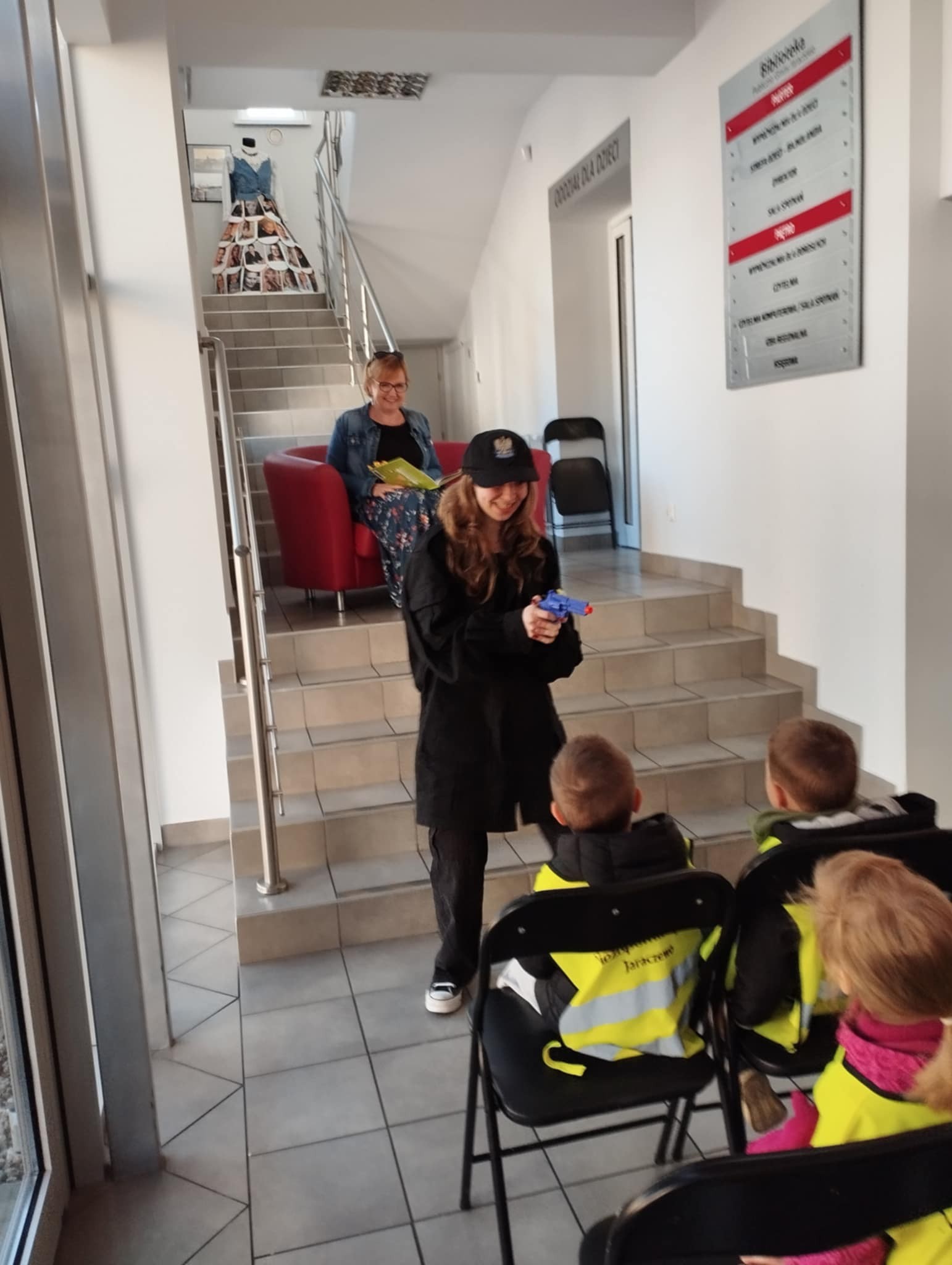 Kobieta w stroju policjanta stoi przed grupą dzieci.