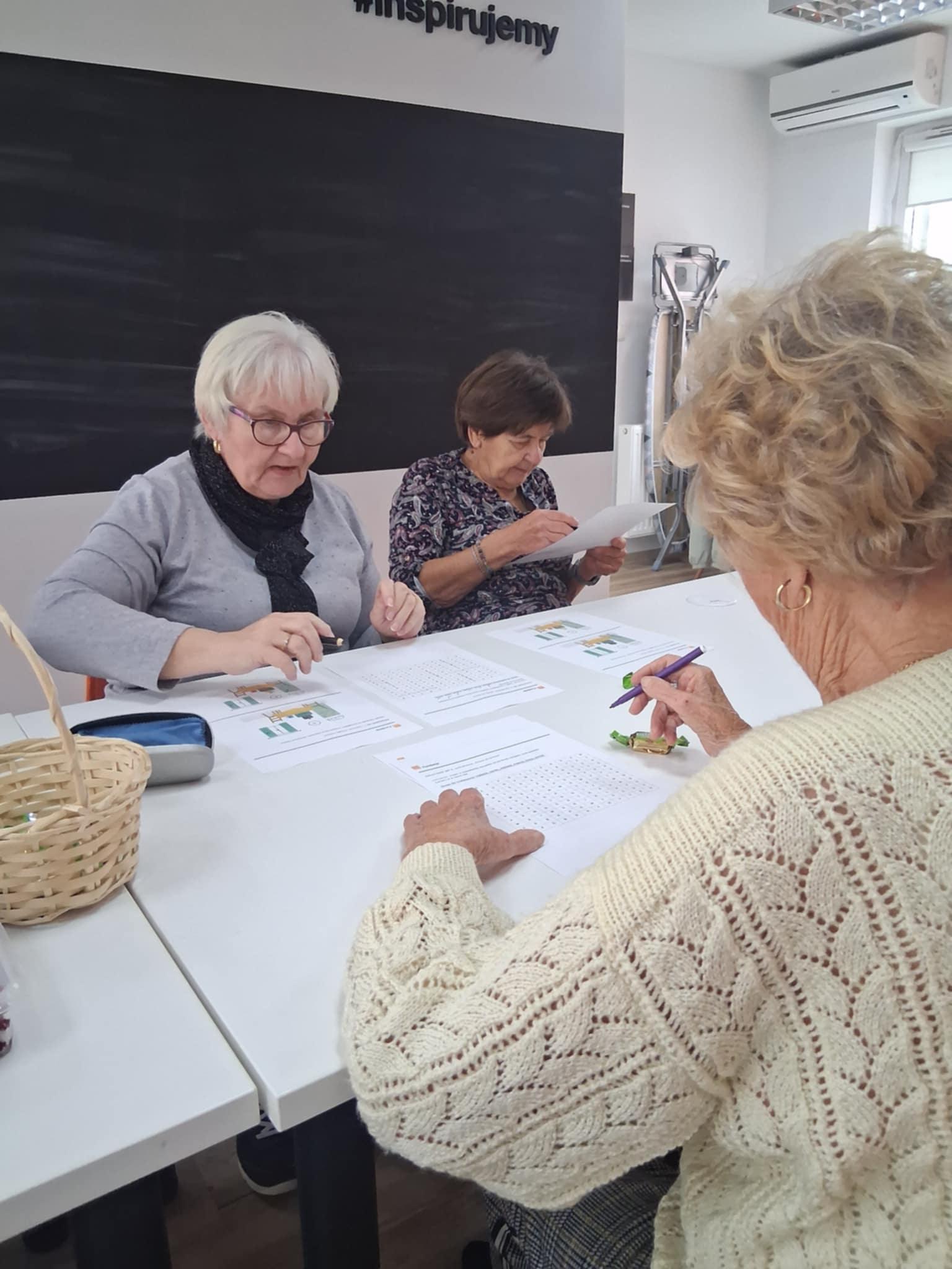 na zdjęciu seniorki przy stole z przepisami