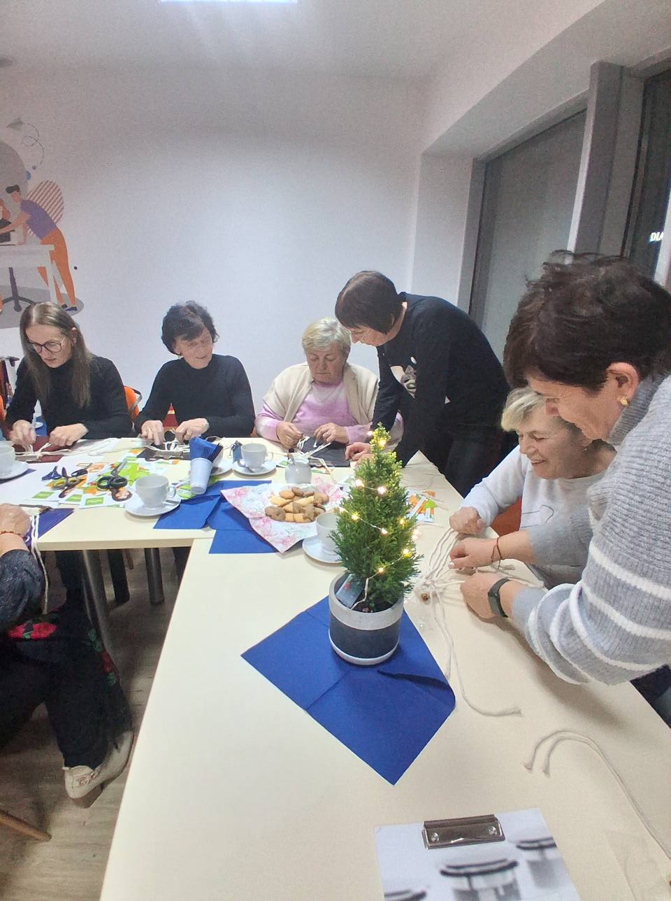 na zdjęciu sześć osób przy stole robiących makramę