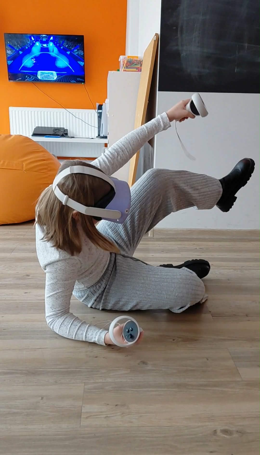 dziewczynka siedzi na podłodze i ma założone gogle VR