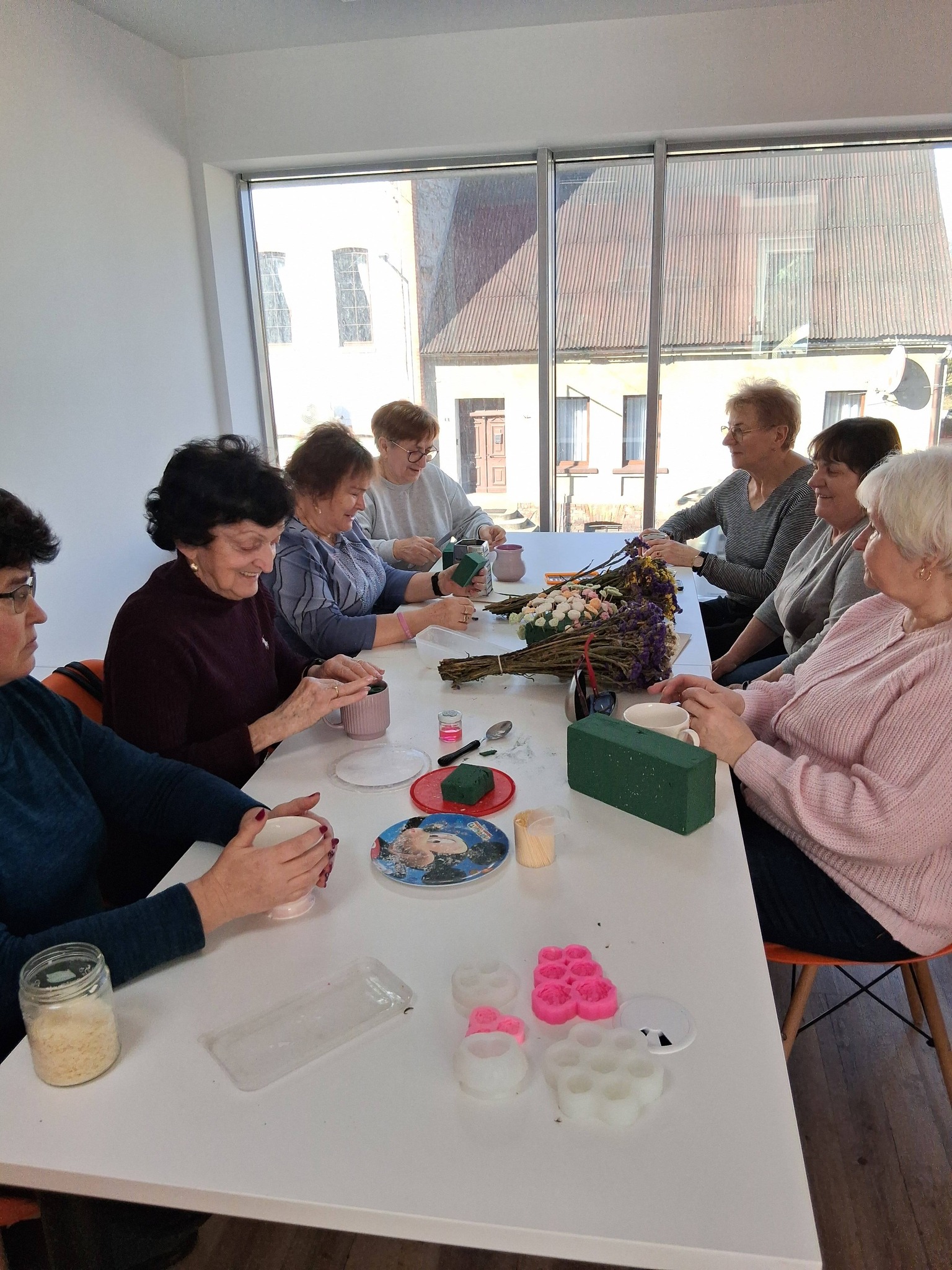 seniorzy pracują przy stole nad powstaniem komozycji