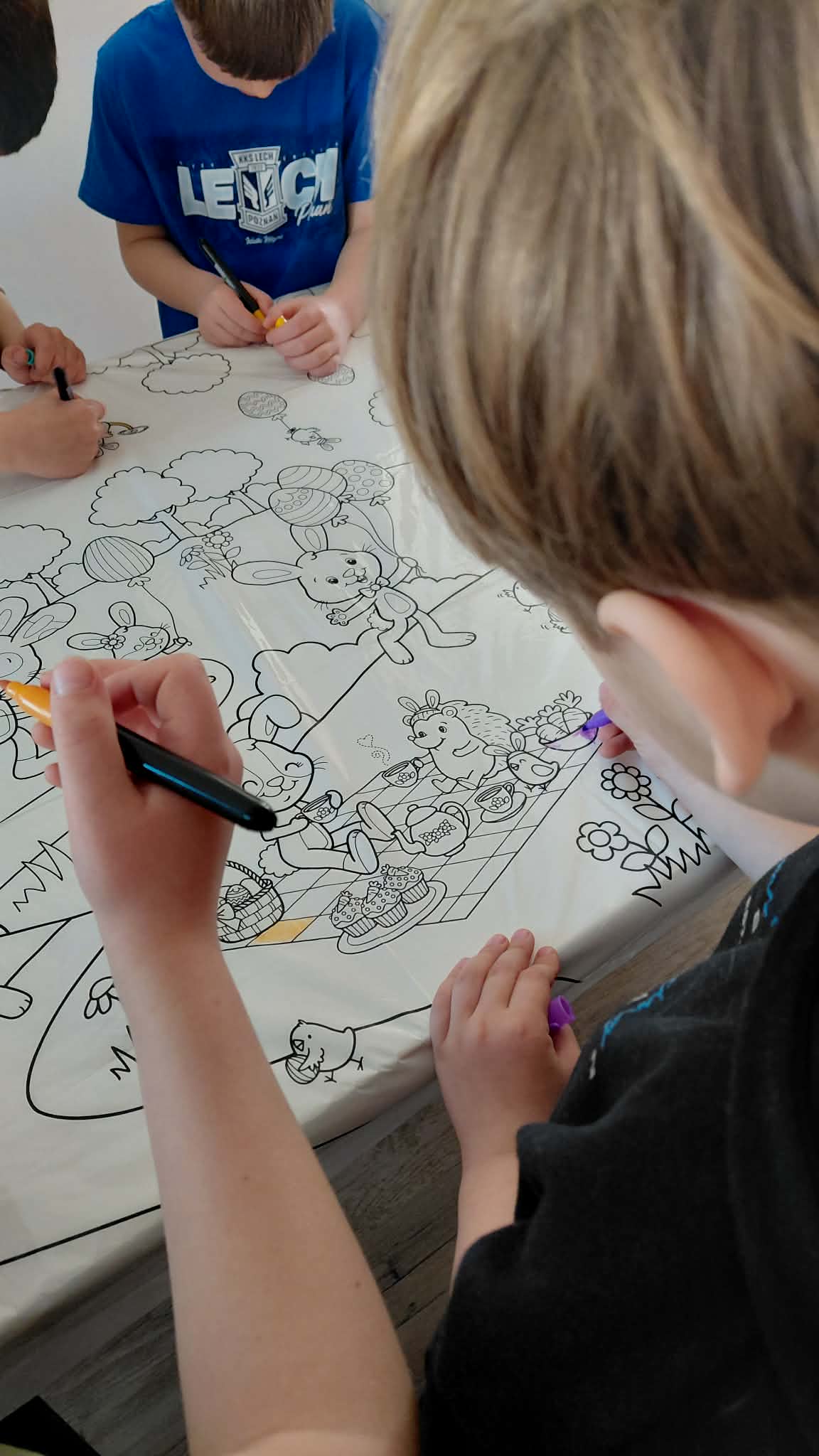 dzieci kolorują dużą wielkanocną kolorowankę