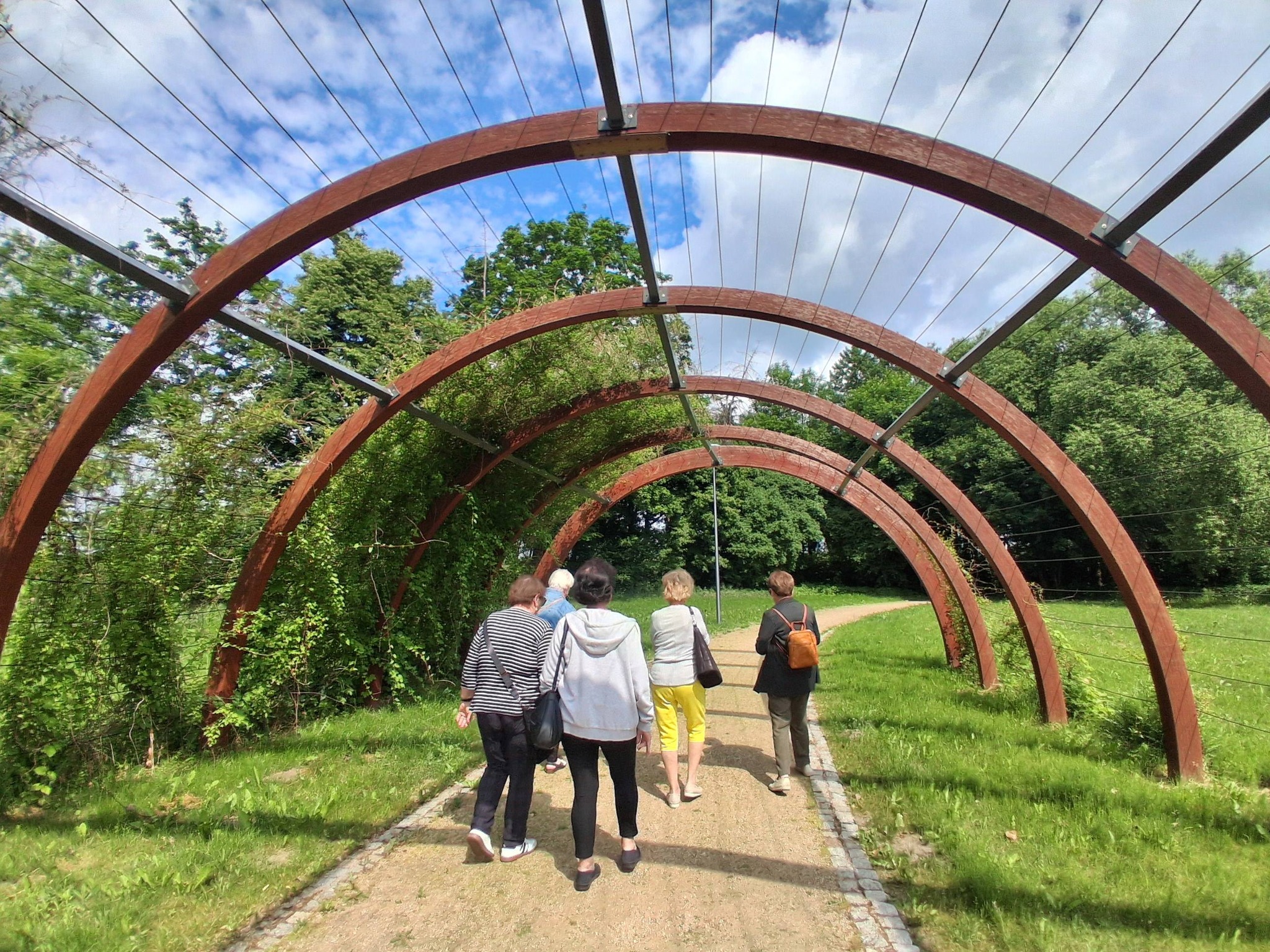 panie spacerują po parku, przechodzą pod zieloną kopułą