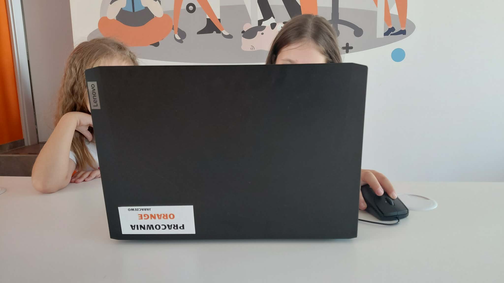 za laptopa widać dzieci, które tworzą kartkę