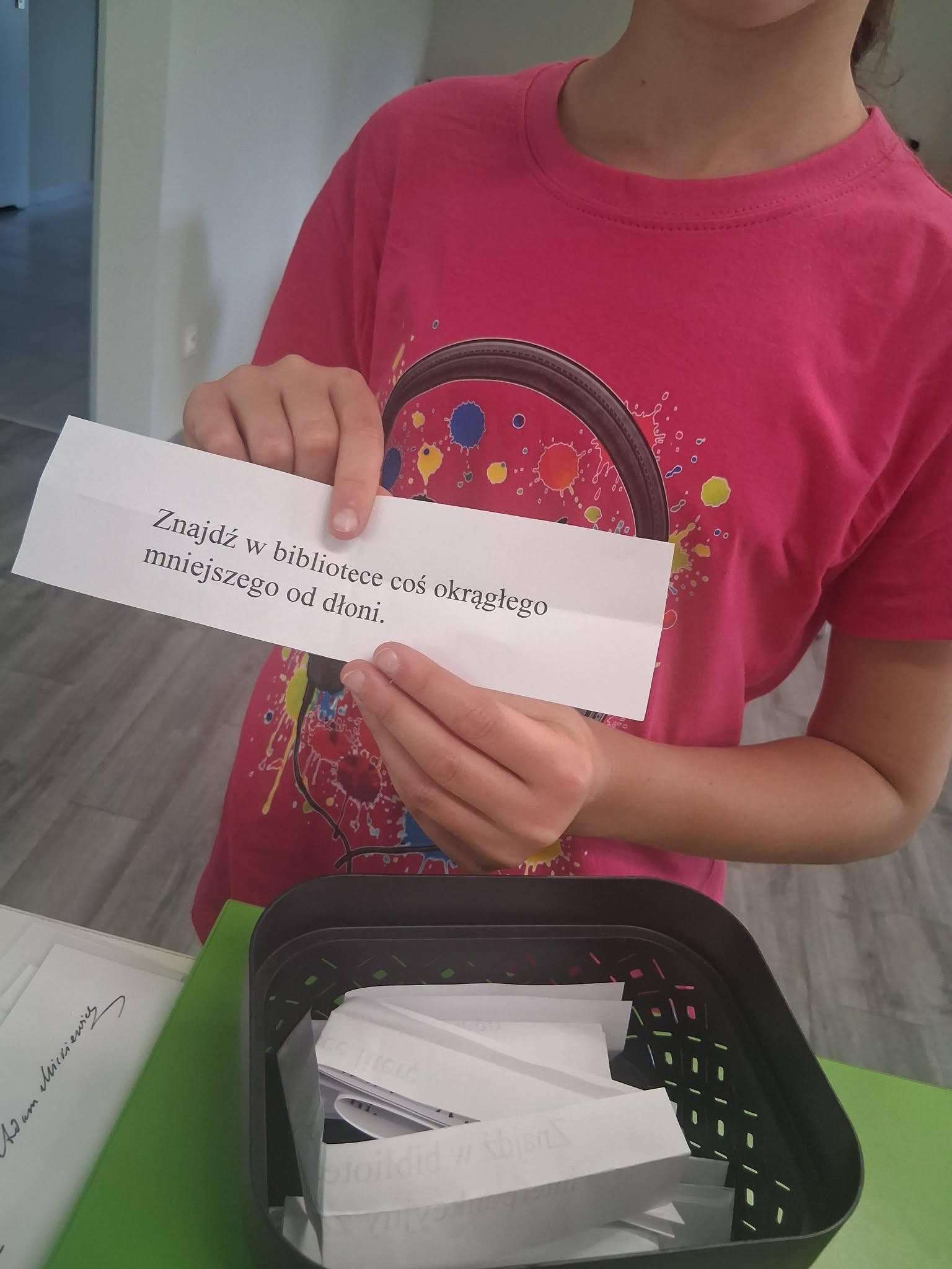 dziewczynka trzyma kartkę z zadaniem